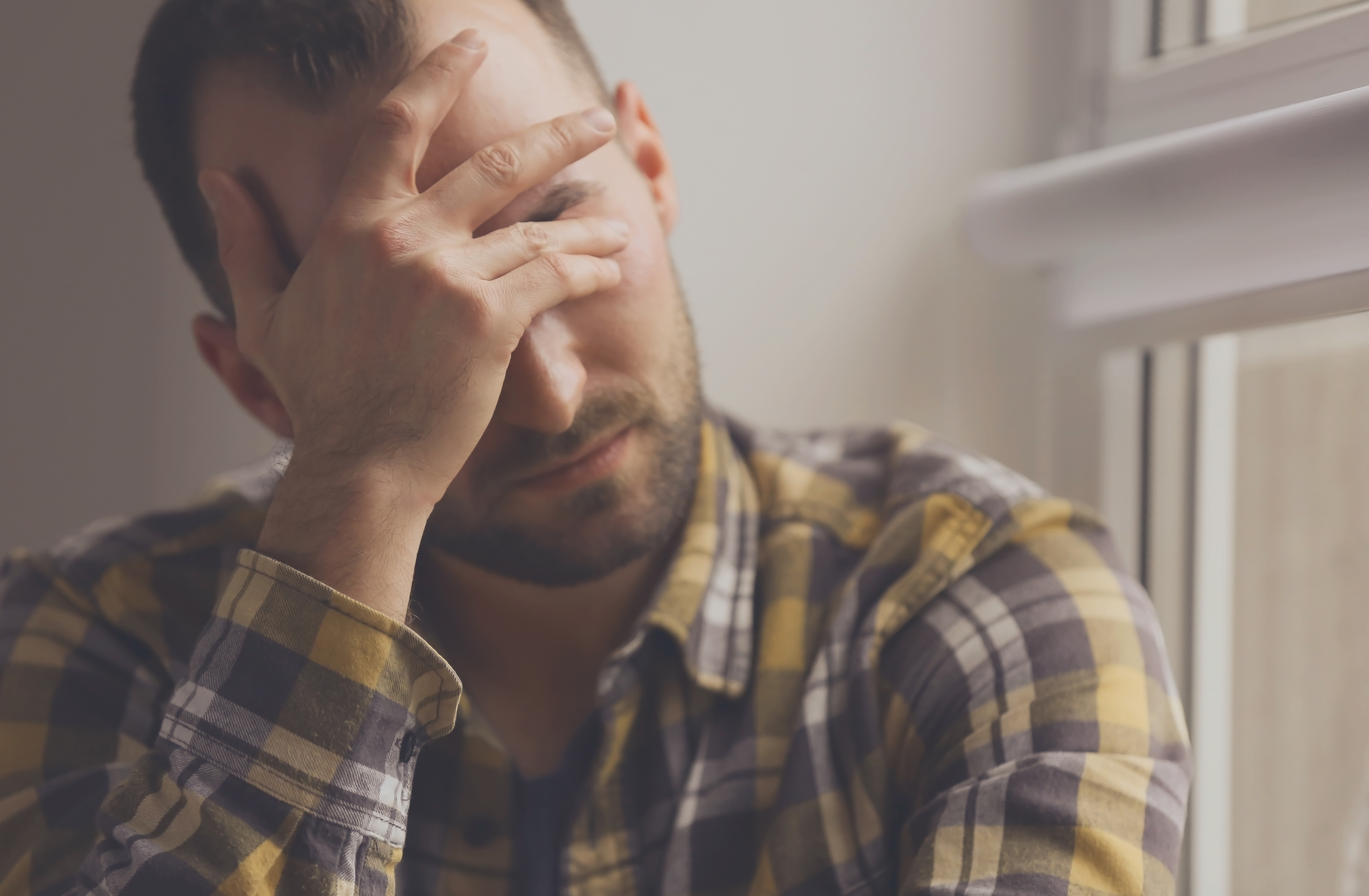 Hombre guapo y deprimido cerca de una ventana, primer plano. | Fuente: Shutterstock