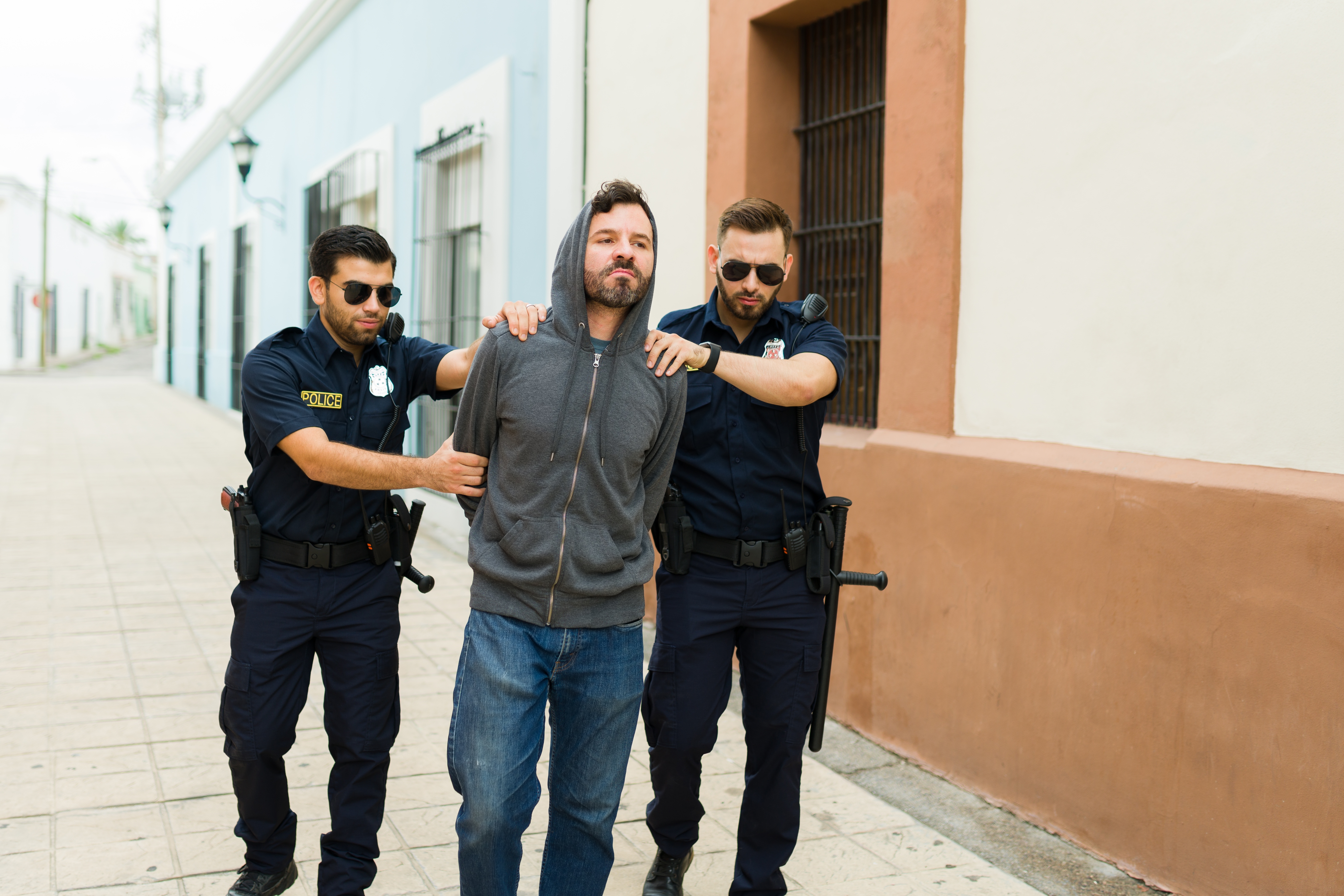 Delincuente violento con capucha siendo detenido por la policía | Fuente: Shutterstock.com