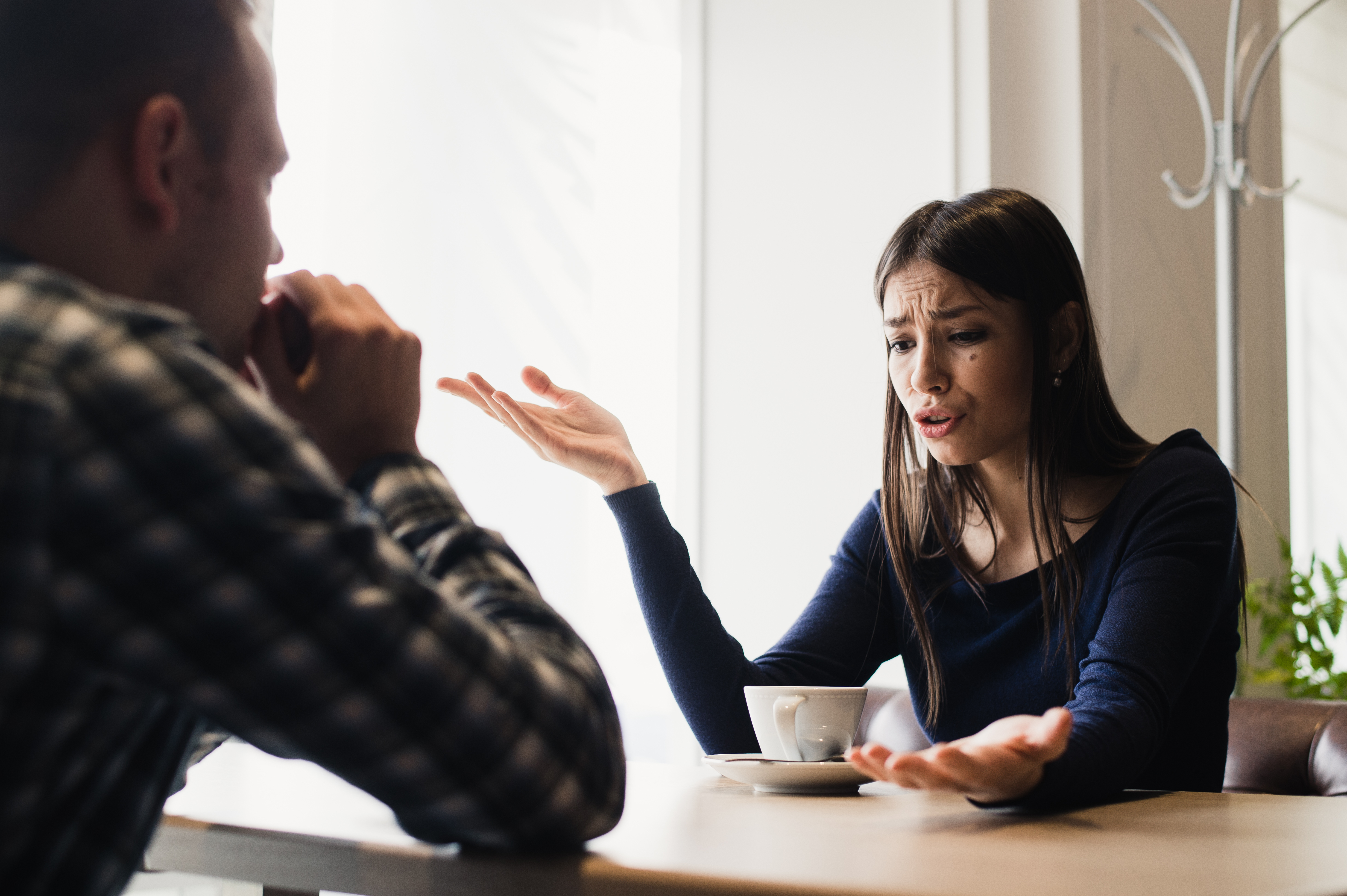 Una mujer triste cuenta una historia a un joven en una cafetería. | Fuente: Shutterstock