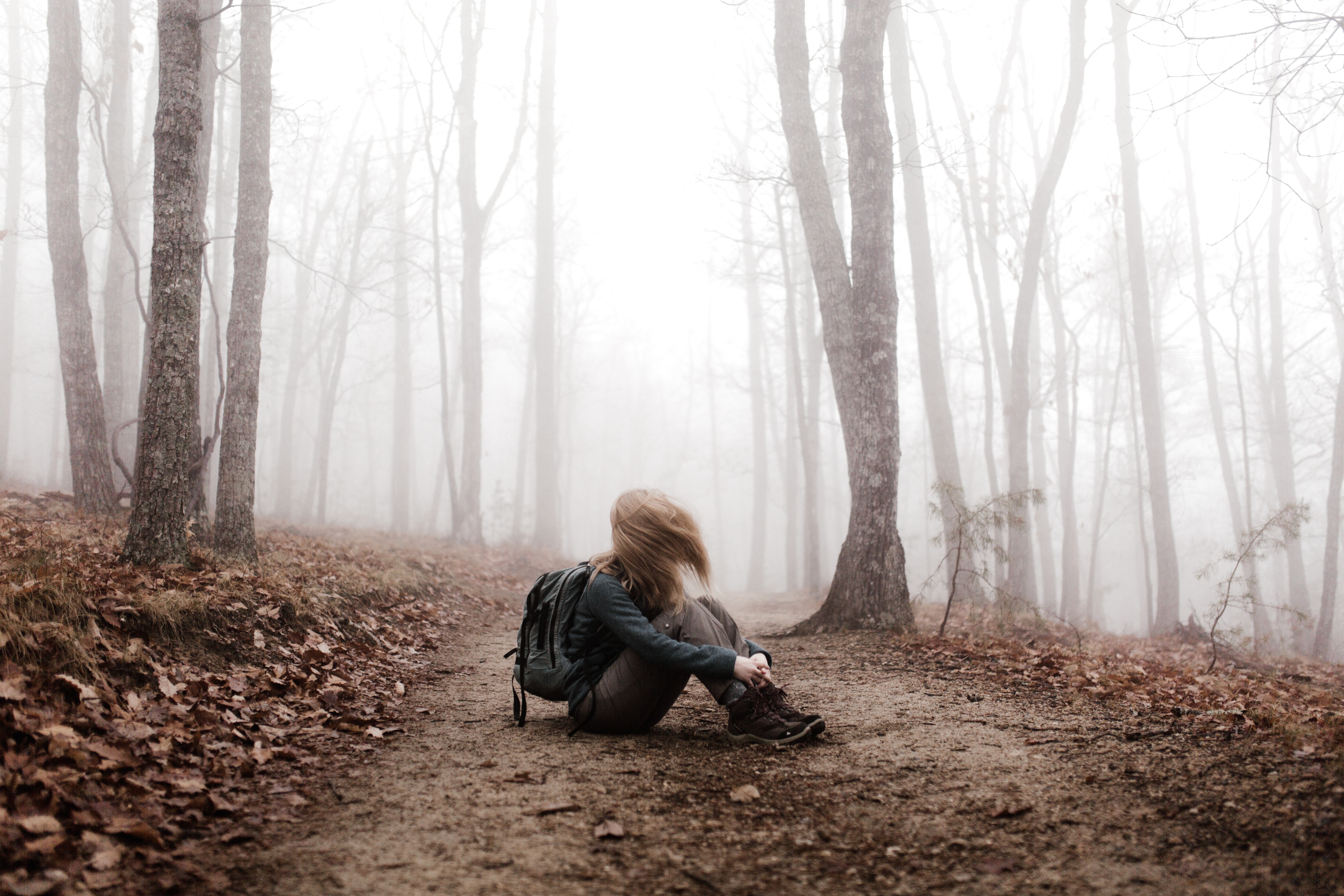 A woman sitting amongst trees. | Source: Unsplash