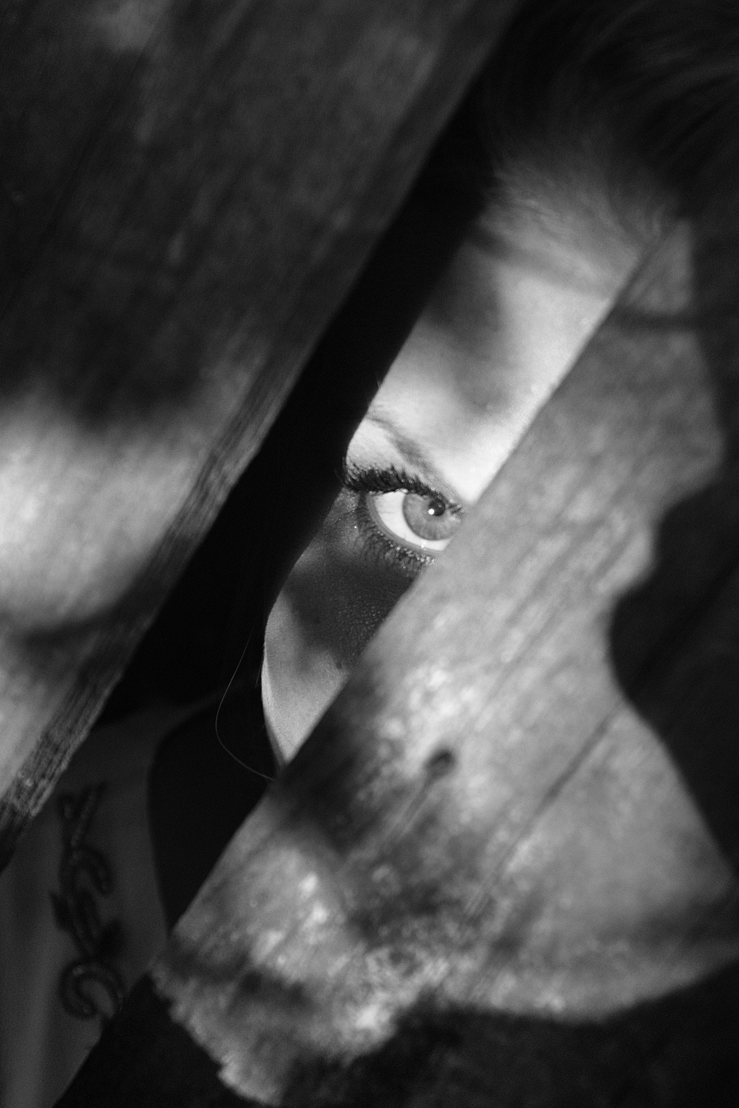 A woman peaking through wooden boards.  | Source: Pexels