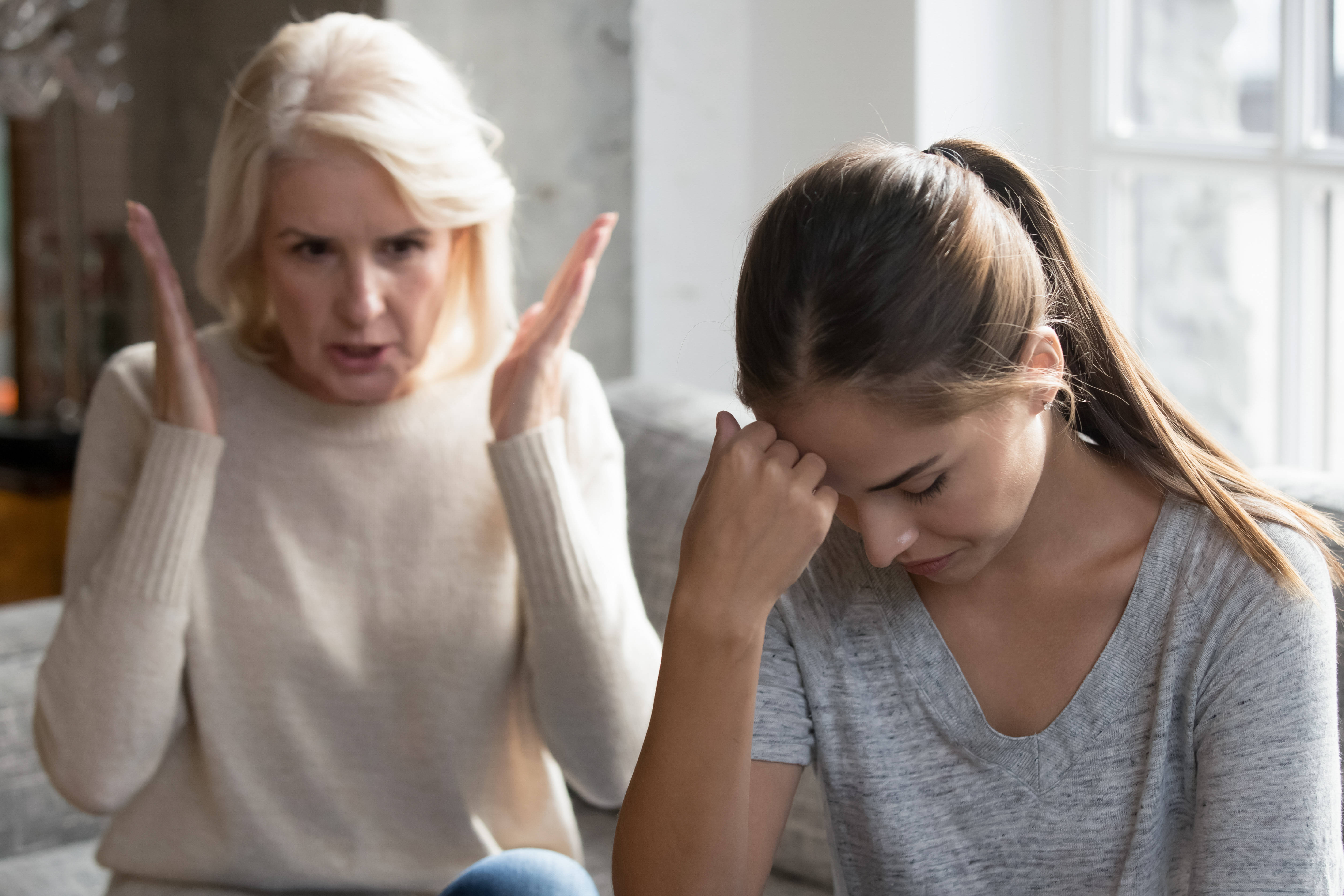 Suegra sentada en el sofá regaña a nuera. | Fuente: Shutterstock