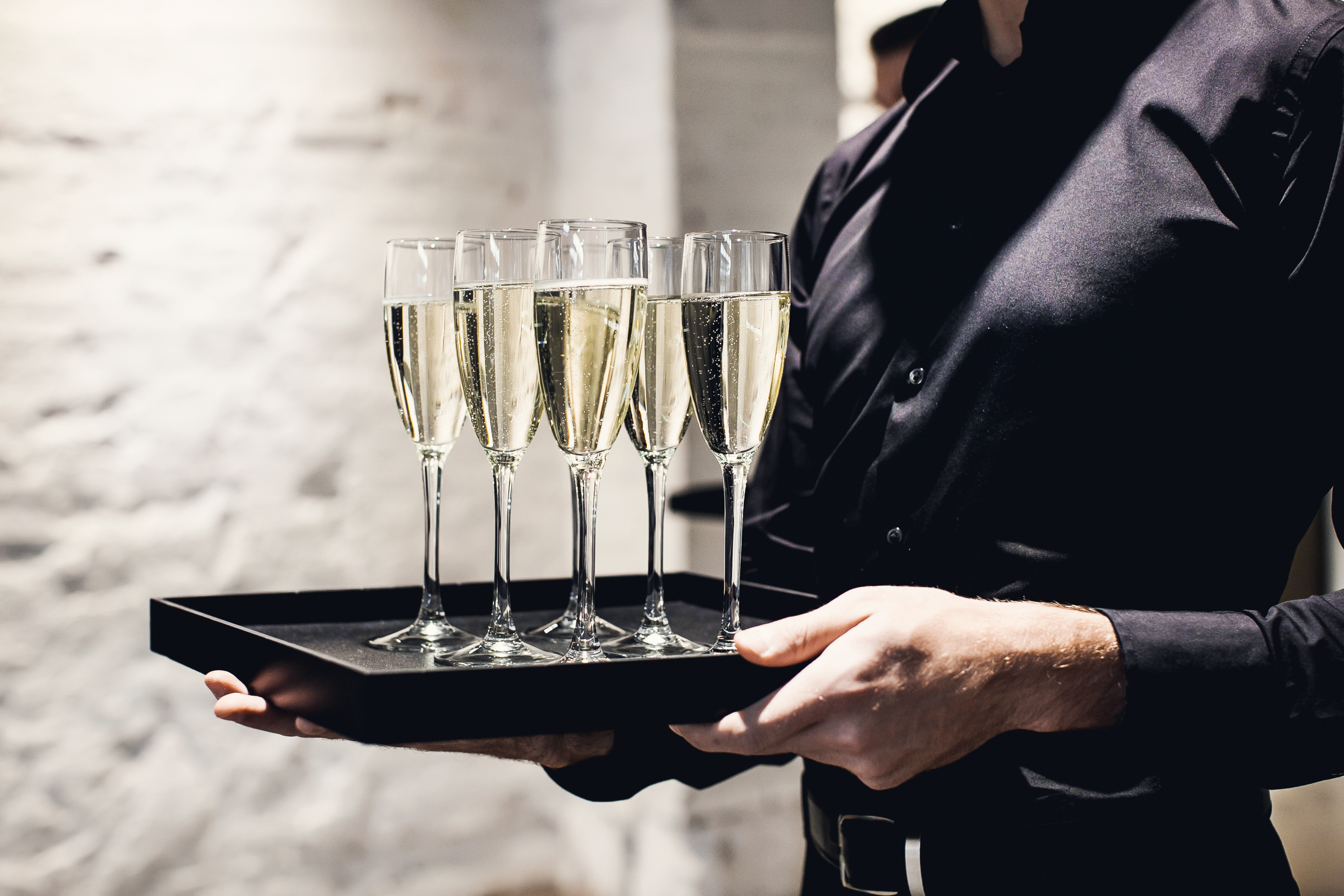 Un camarero sostiene copas con champán servido en una bandeja. | Fuente: Shutterstock