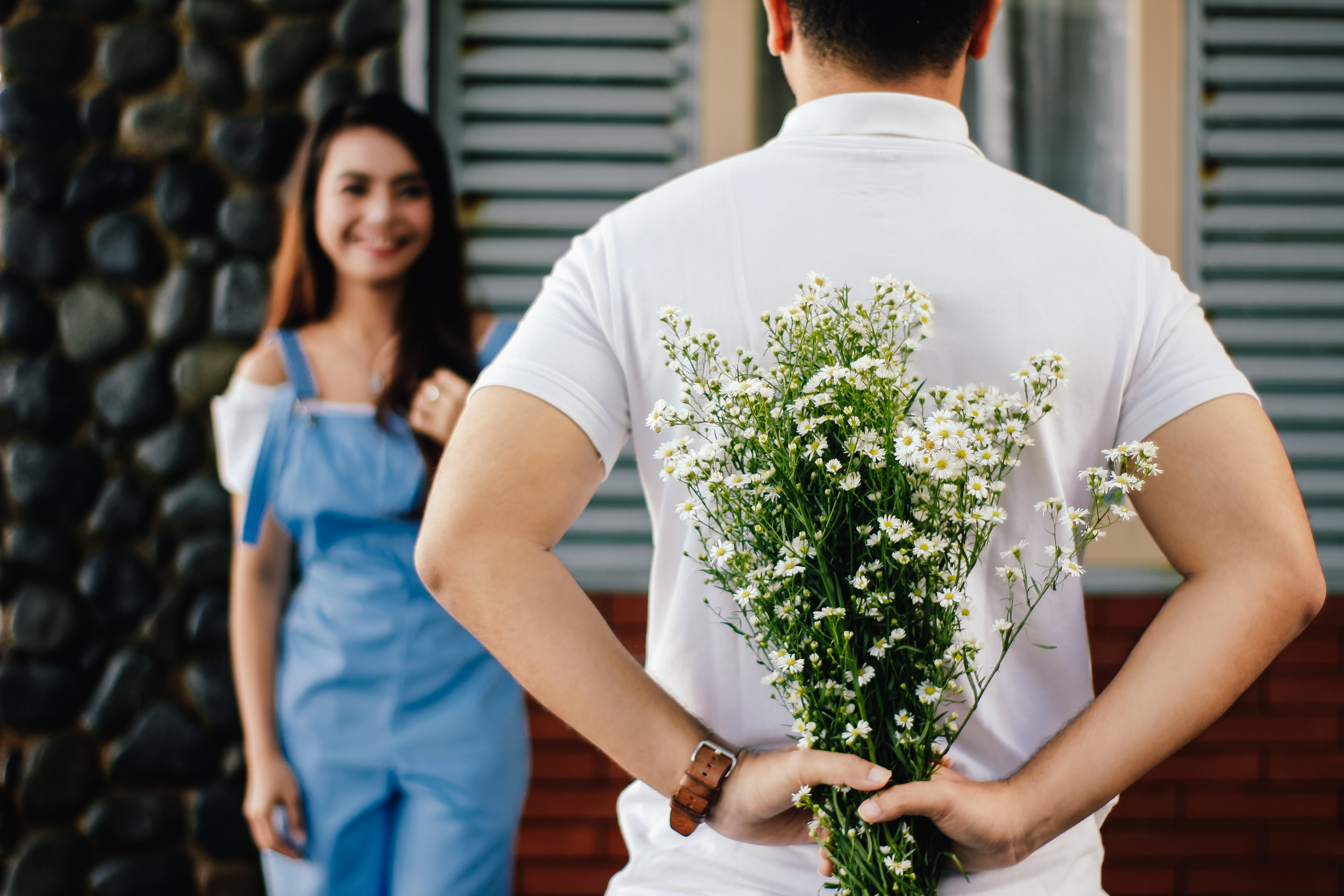 Man Holding Baby's-breath Flower in Front of Woman Standing Near Marble Wall. | Source: Pexels