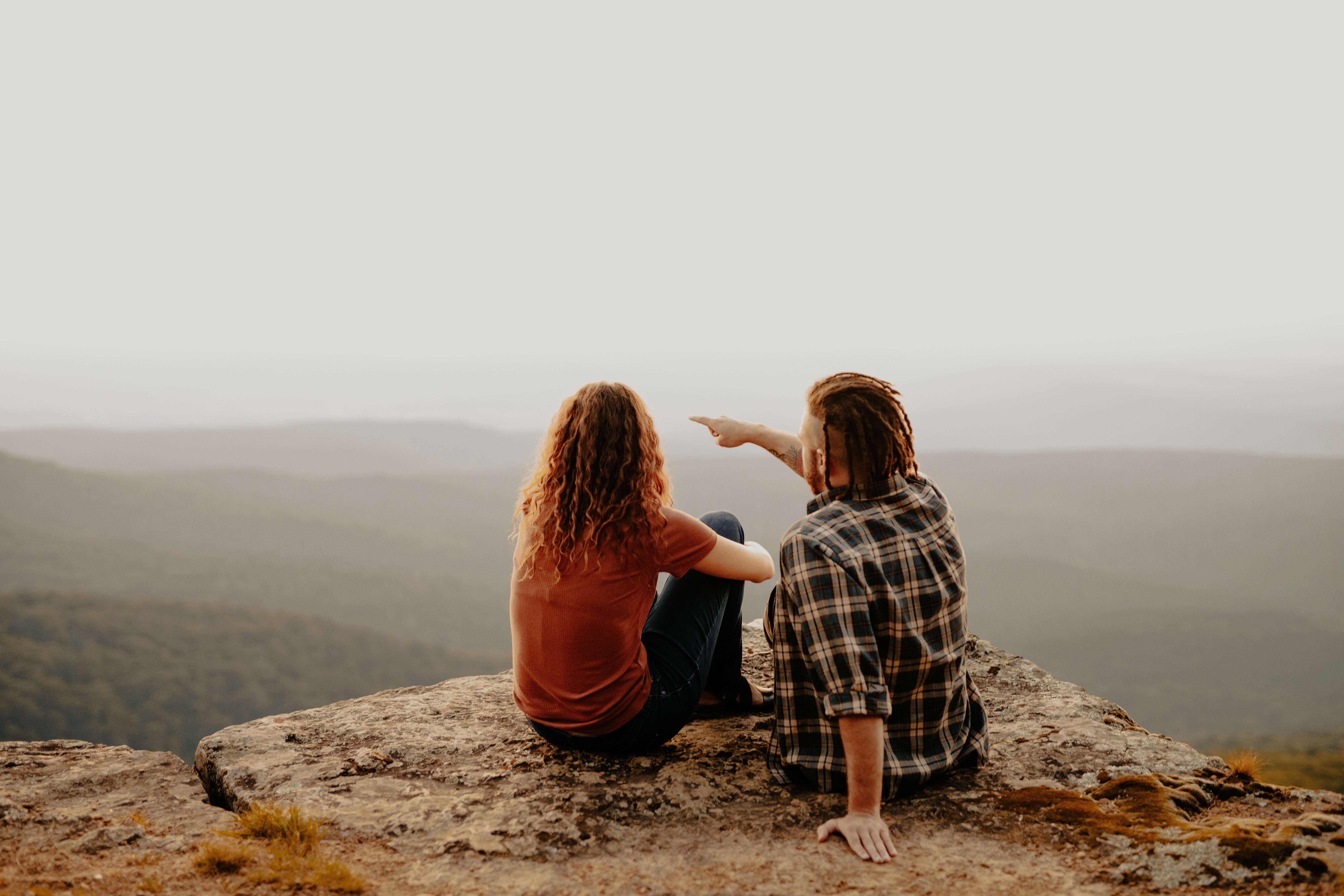 A couple sitting on a cliff. | Source: Unsplash
