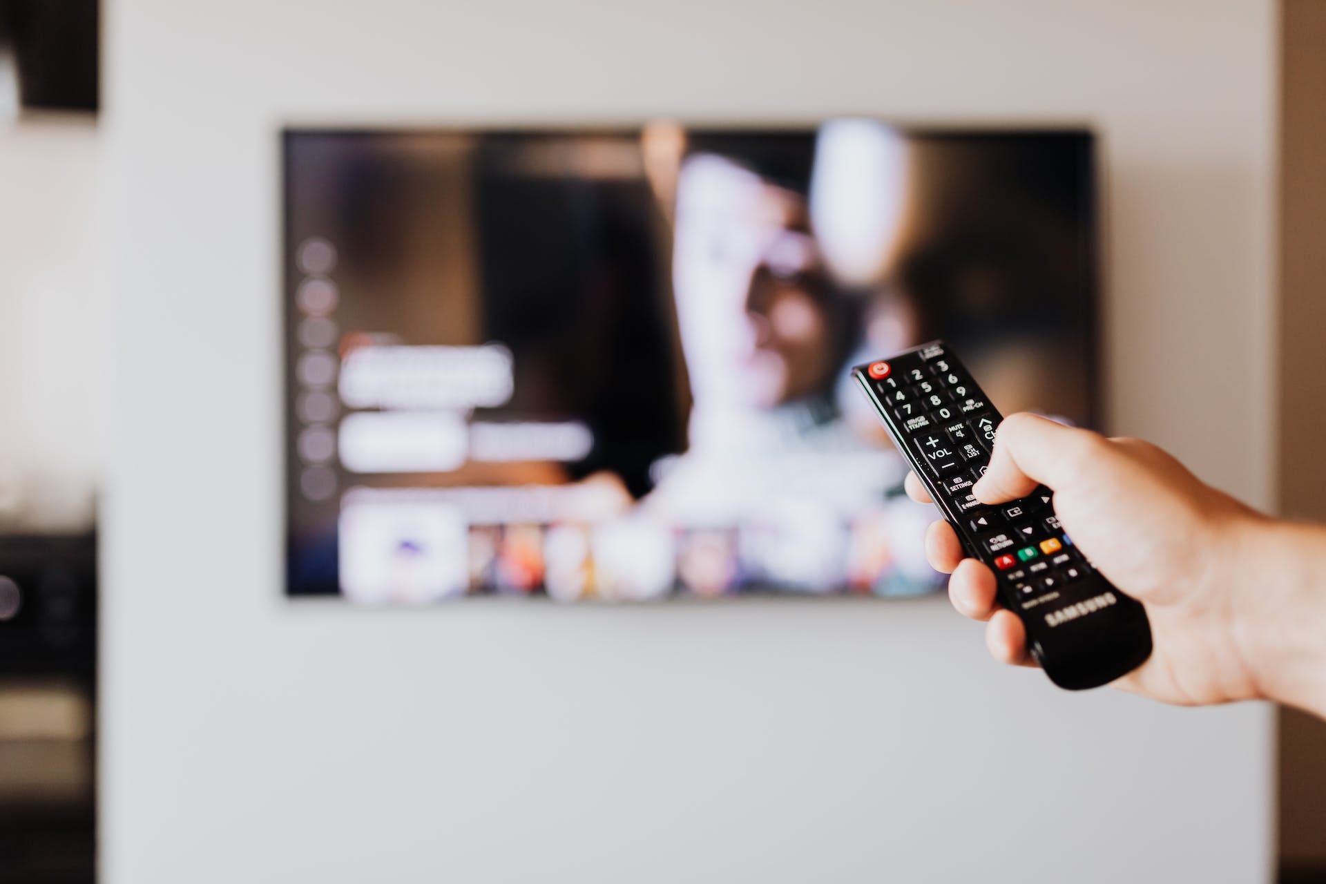 A person pressing the button of a TV remote control | Source: Pexels