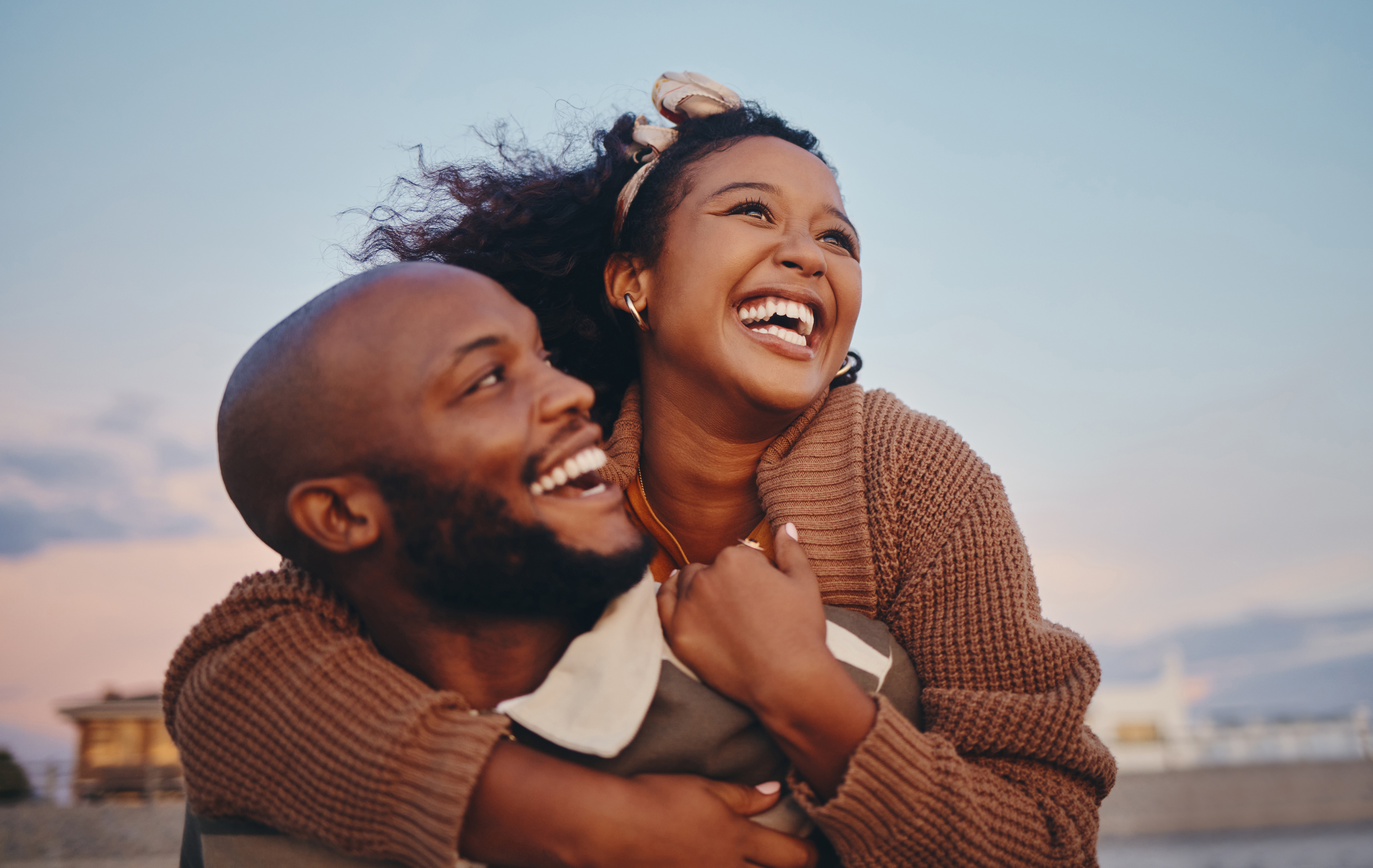 Happy black couple, hug and laugh while enjoying bonding time together in the outdoors. | Source: Shutterstock