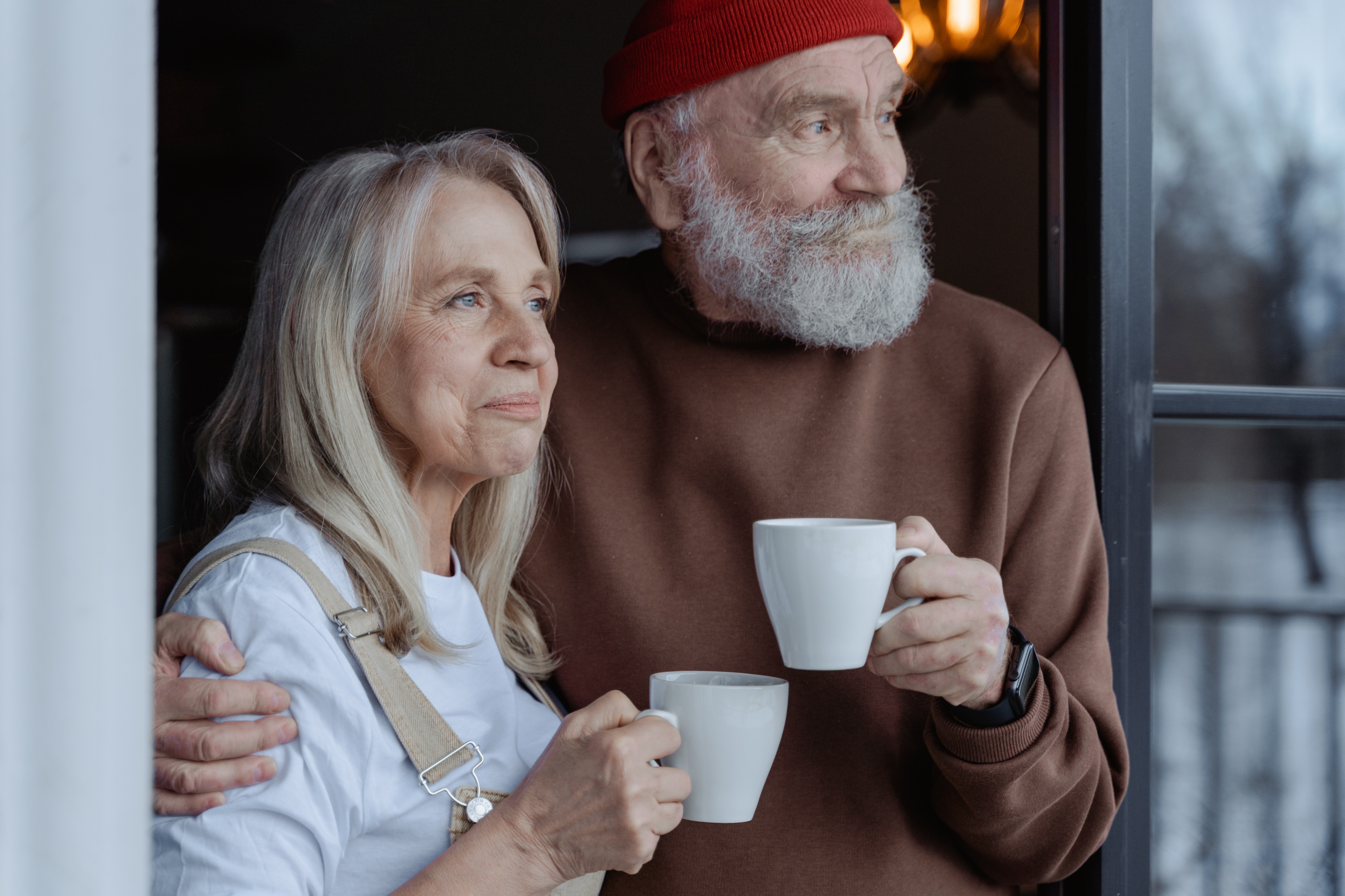 An elderly couple holding mugs. | Source: Pexels