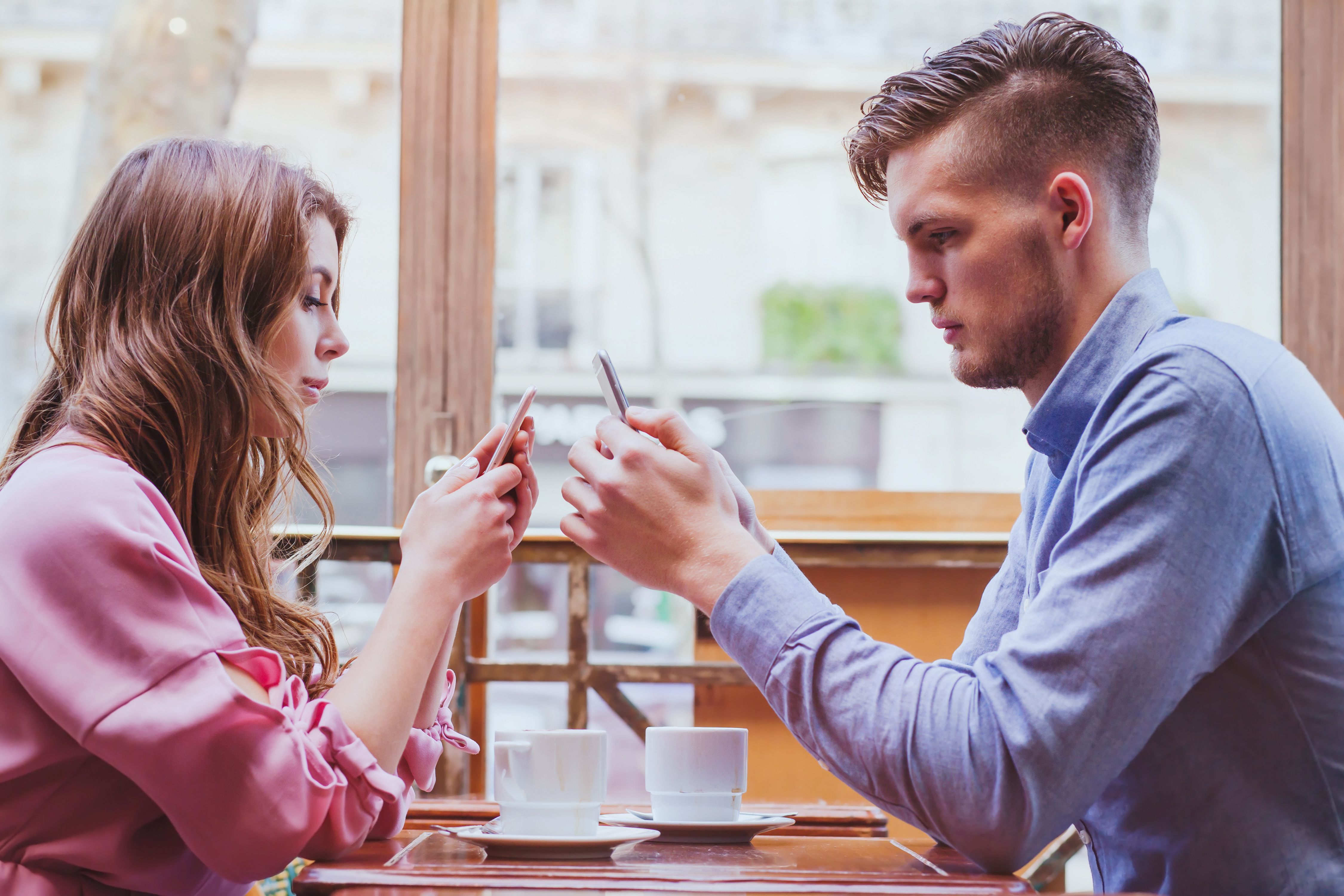 A man and woman using their phones. | Source: Shutterstock