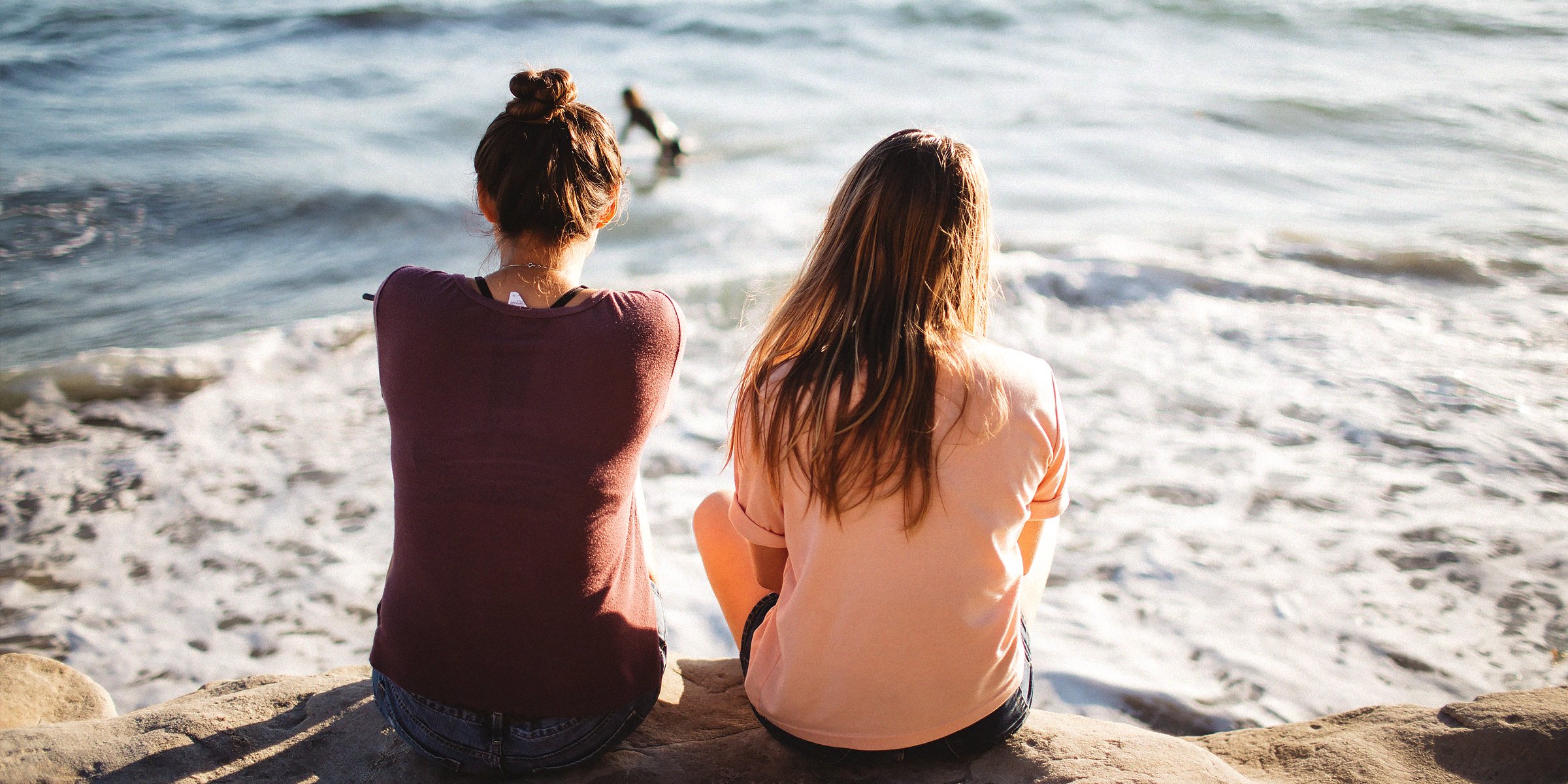 Two girls sitting in front of a sea | Source: Unsplash.com