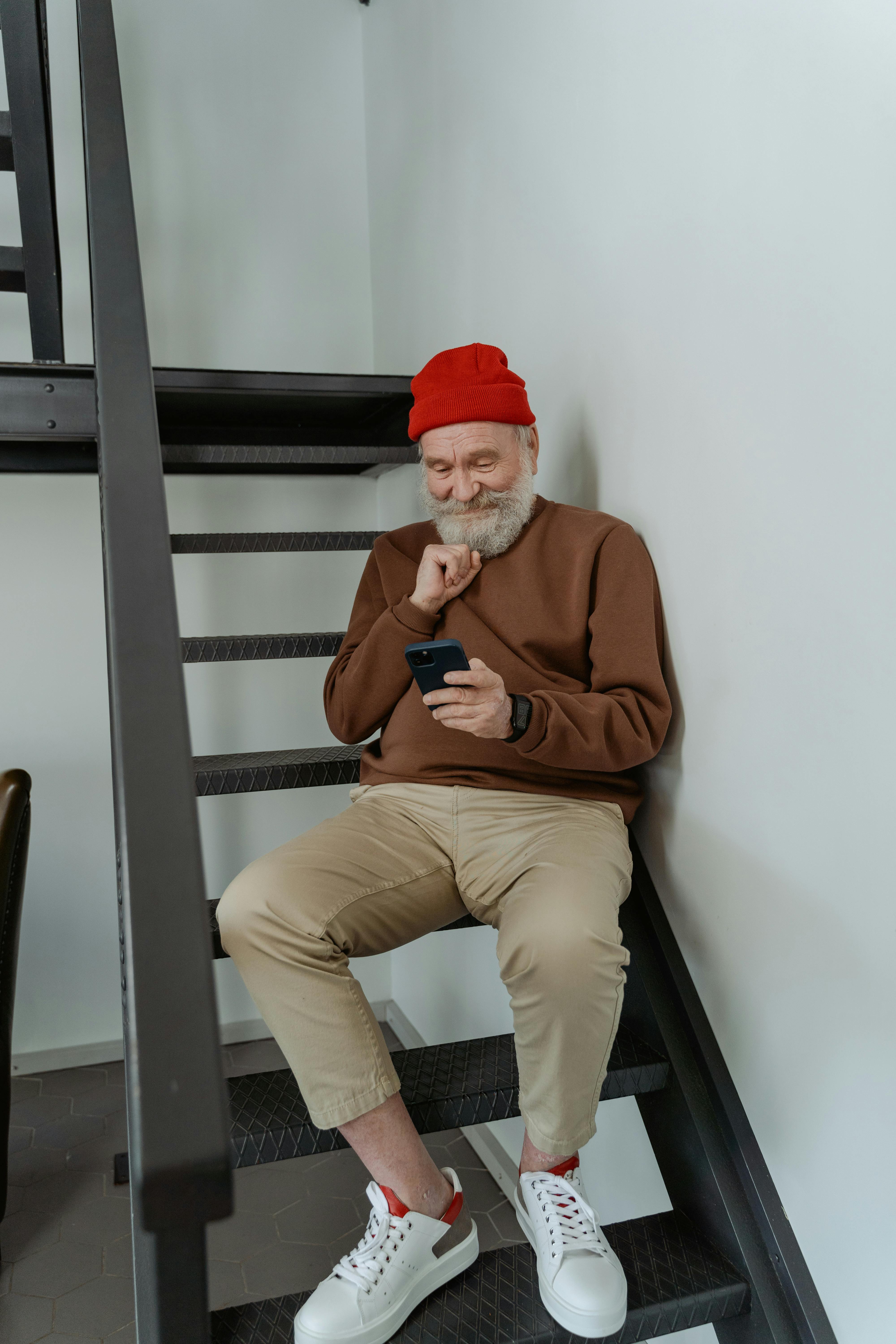 A man staring at his phone while sitting on the stairs, photo uploaded on March 31, 2021. | Source: Pexels