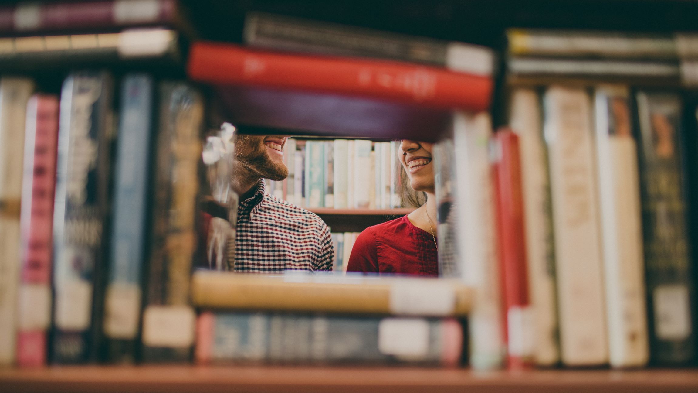 Two people smiling at each other behind books. | Source: Unsplash