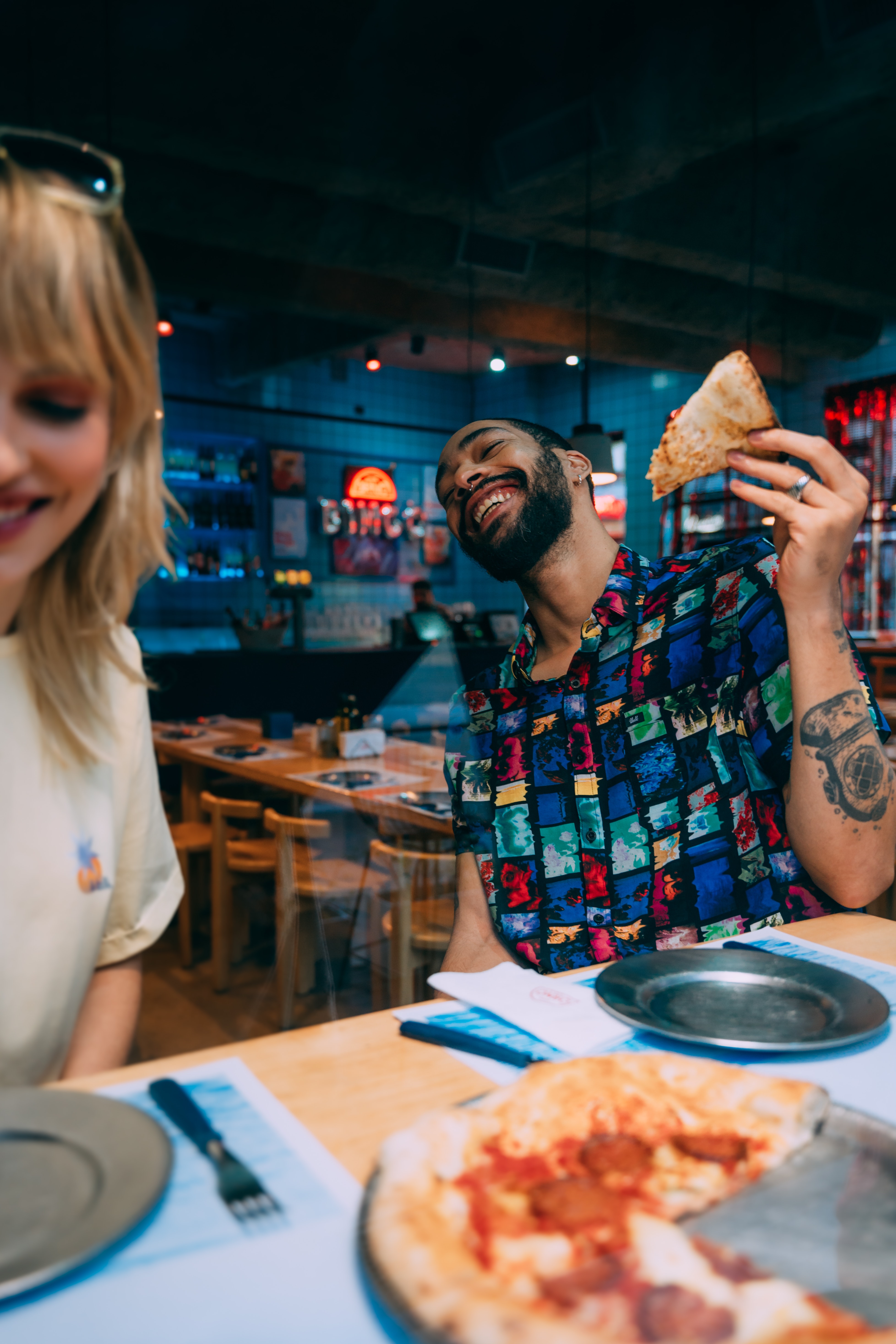 A couple laughing and eating pizza at a bar.  | Source: Pexels