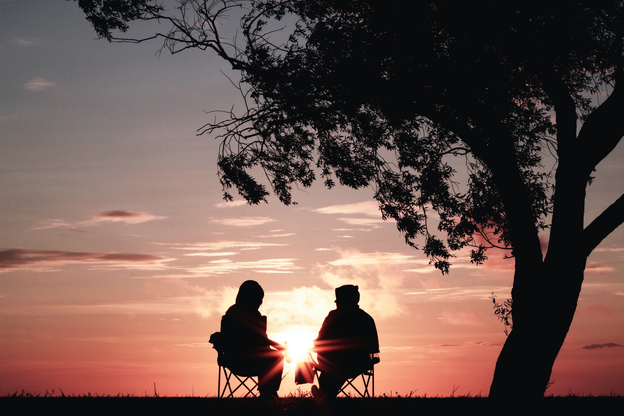 Two people in nature, watching the sunset. | Source: Unsplash