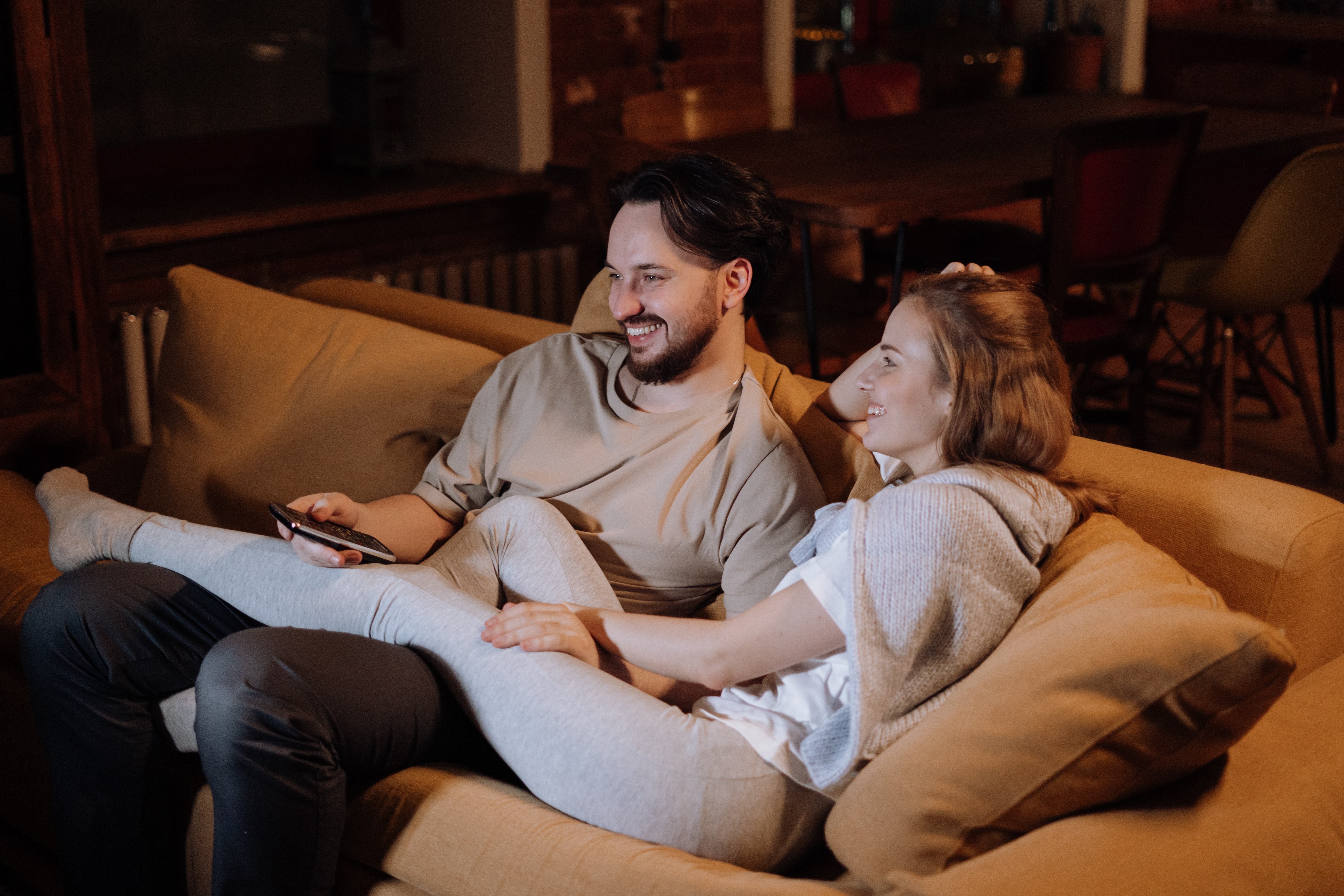 A couple lounges on the couch while watching television. | Source: Pexels