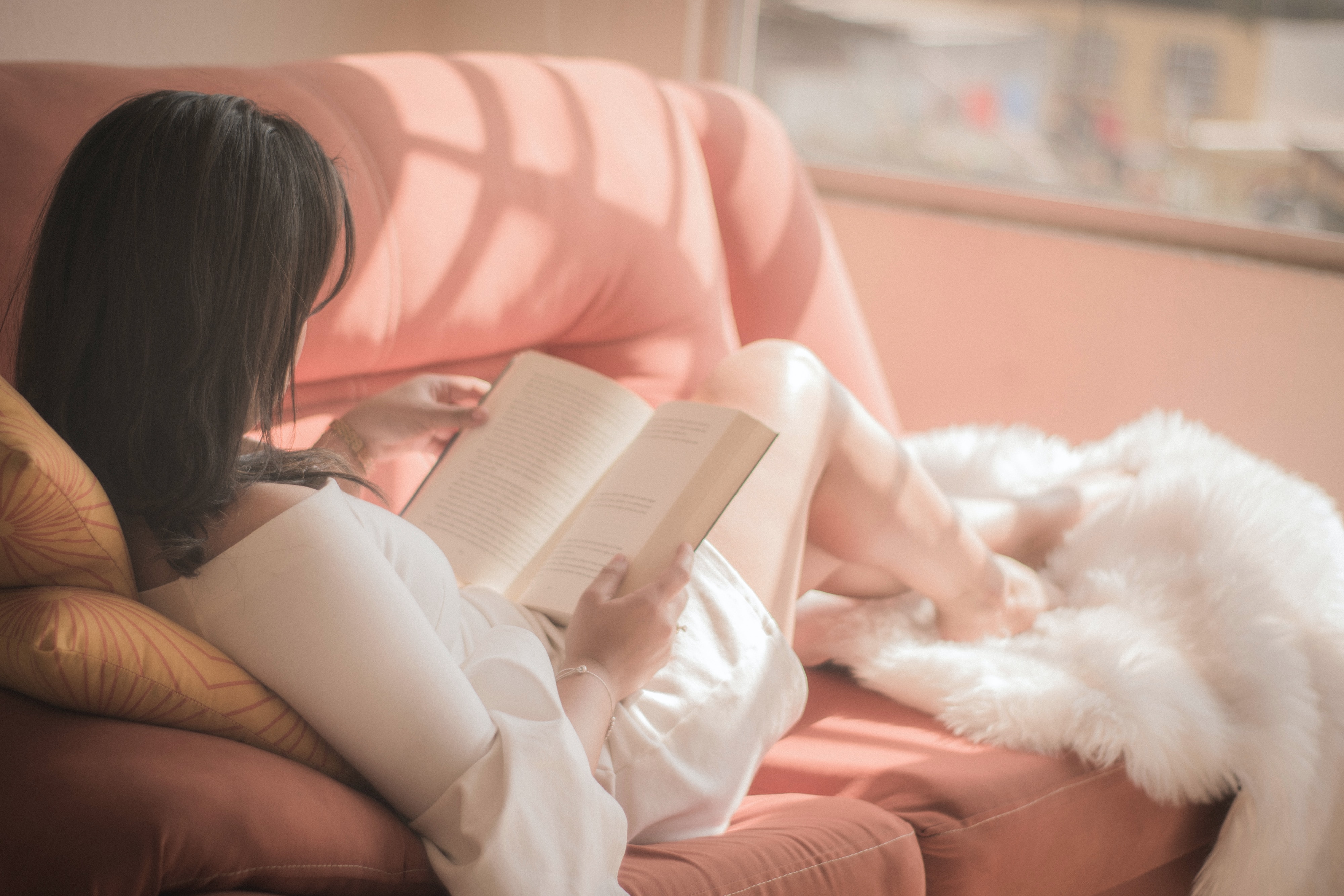 A woman reading while lying on a couch.  | Source: Unsplash