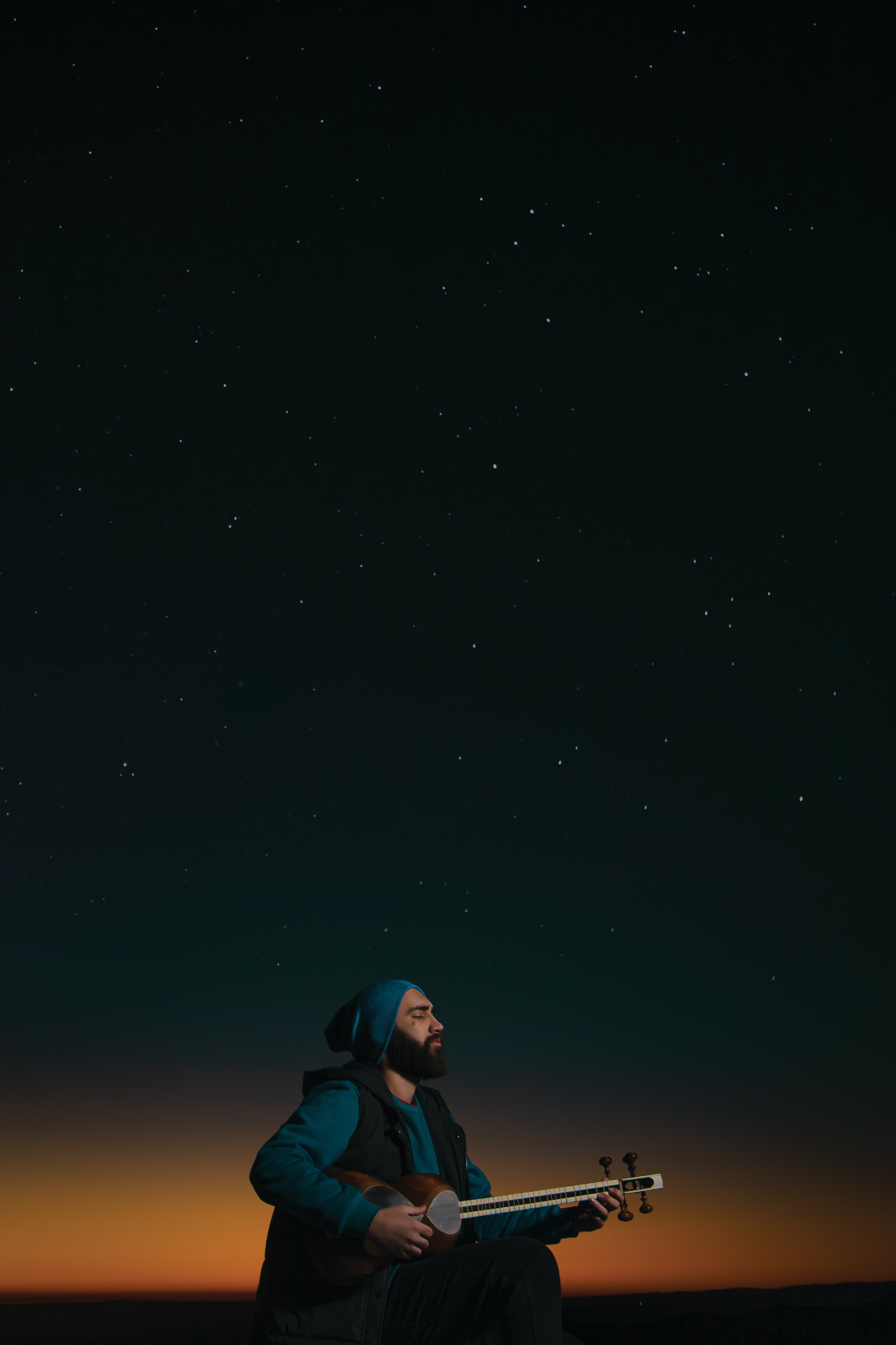 A man playing guitar underneath a starry sky. | Source: Pexels