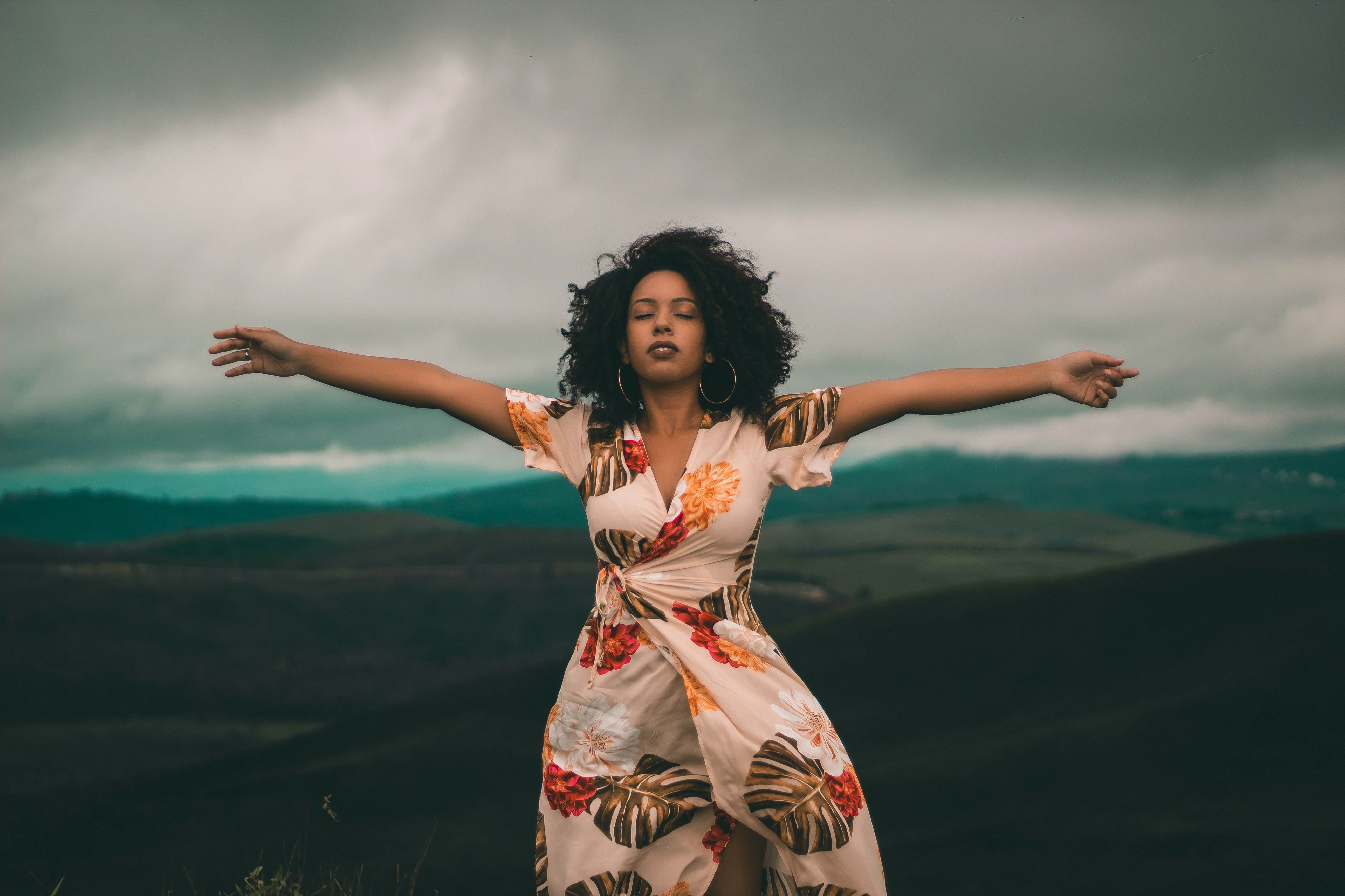 A woman with her eyes closed and her arms wide open. | Source: Pexels.