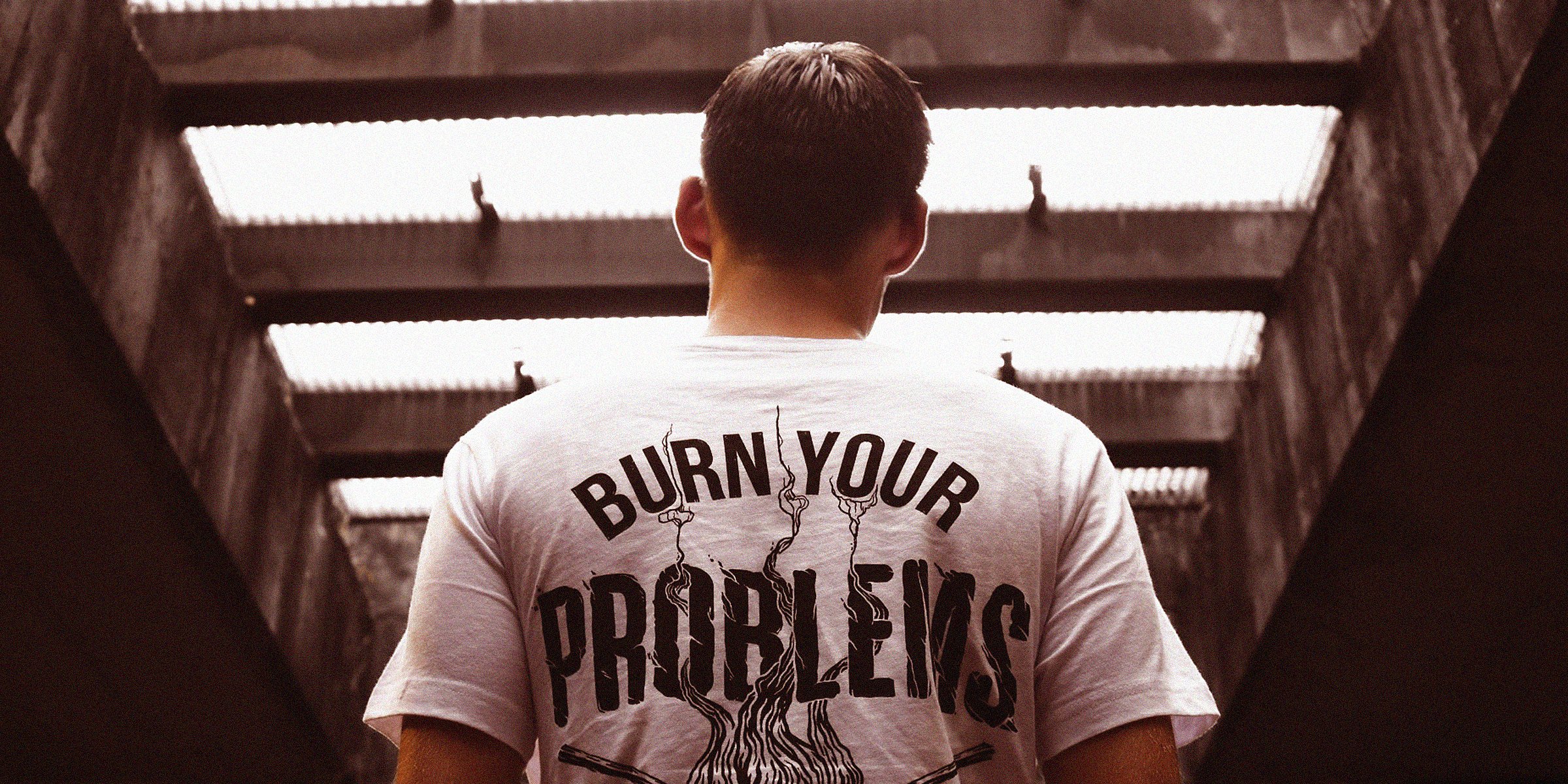 A man facing backward with a t-shirt that reads 'Burn Your Problems' | Image: AmoDays