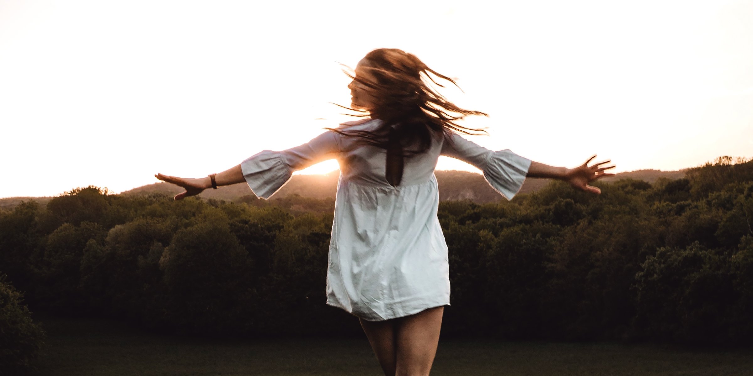 Unsplash | Woman with her arms stretched out against the backdrop of the sunset. 