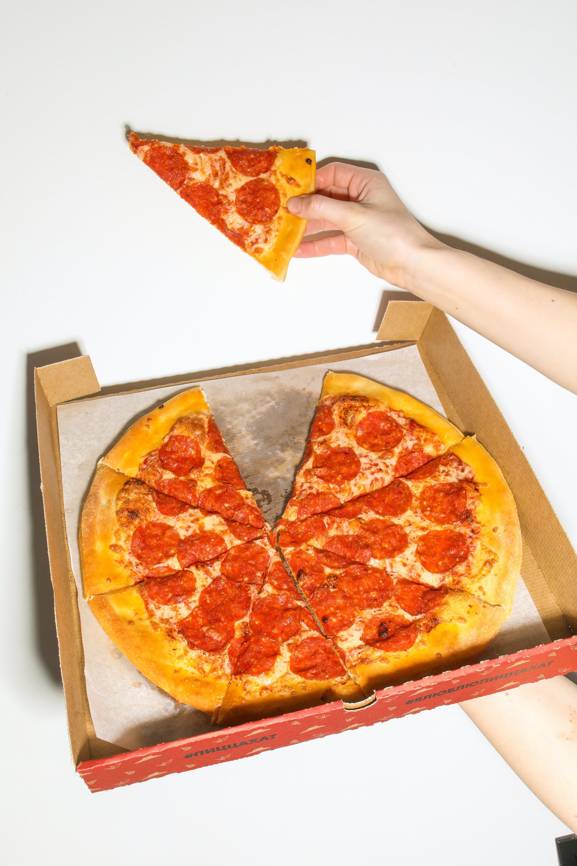A person holding a pizza slice and a box of pizza | Source: Pexels