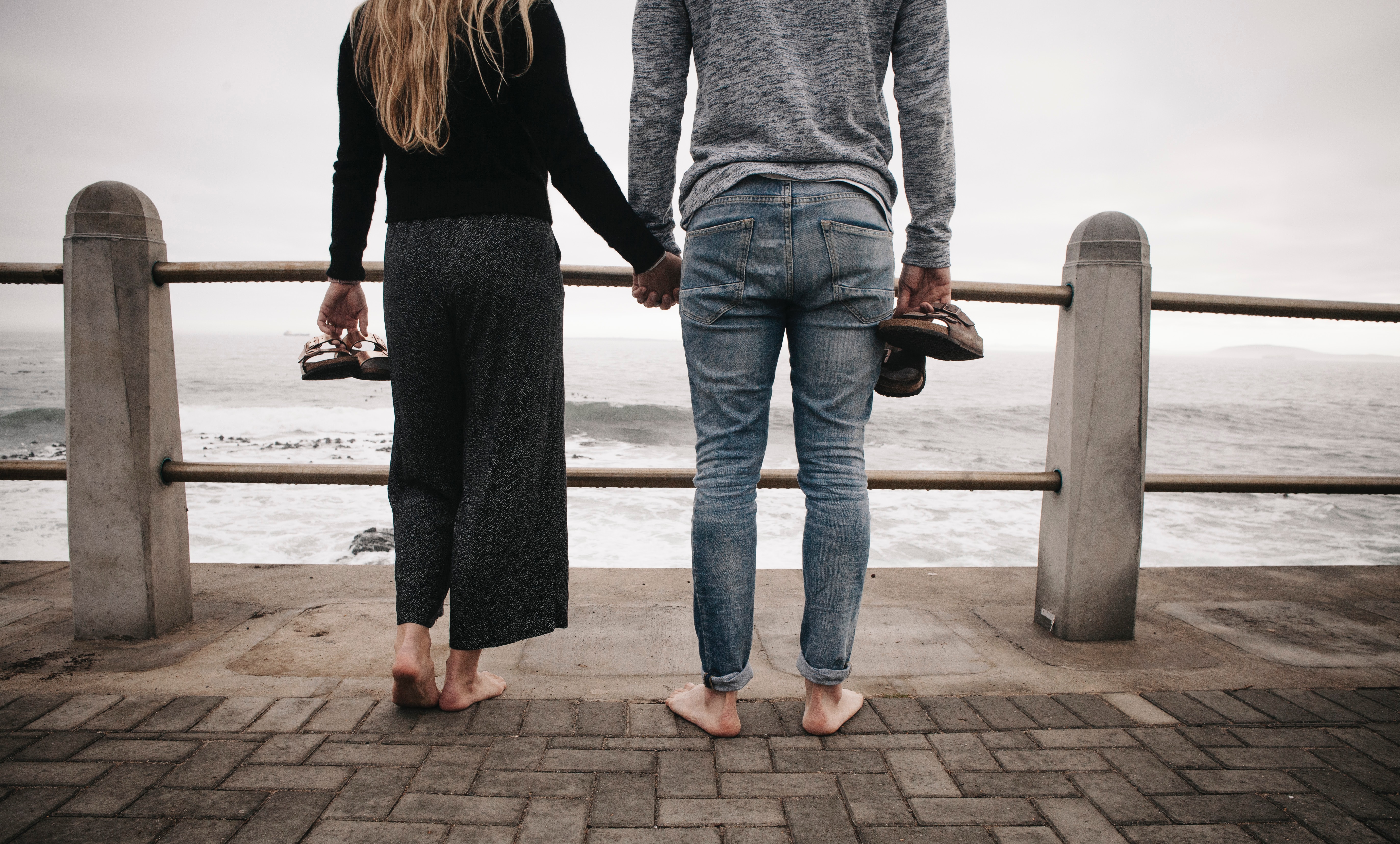 A couple holding hands while looking at the ocean. | Source: Unsplash