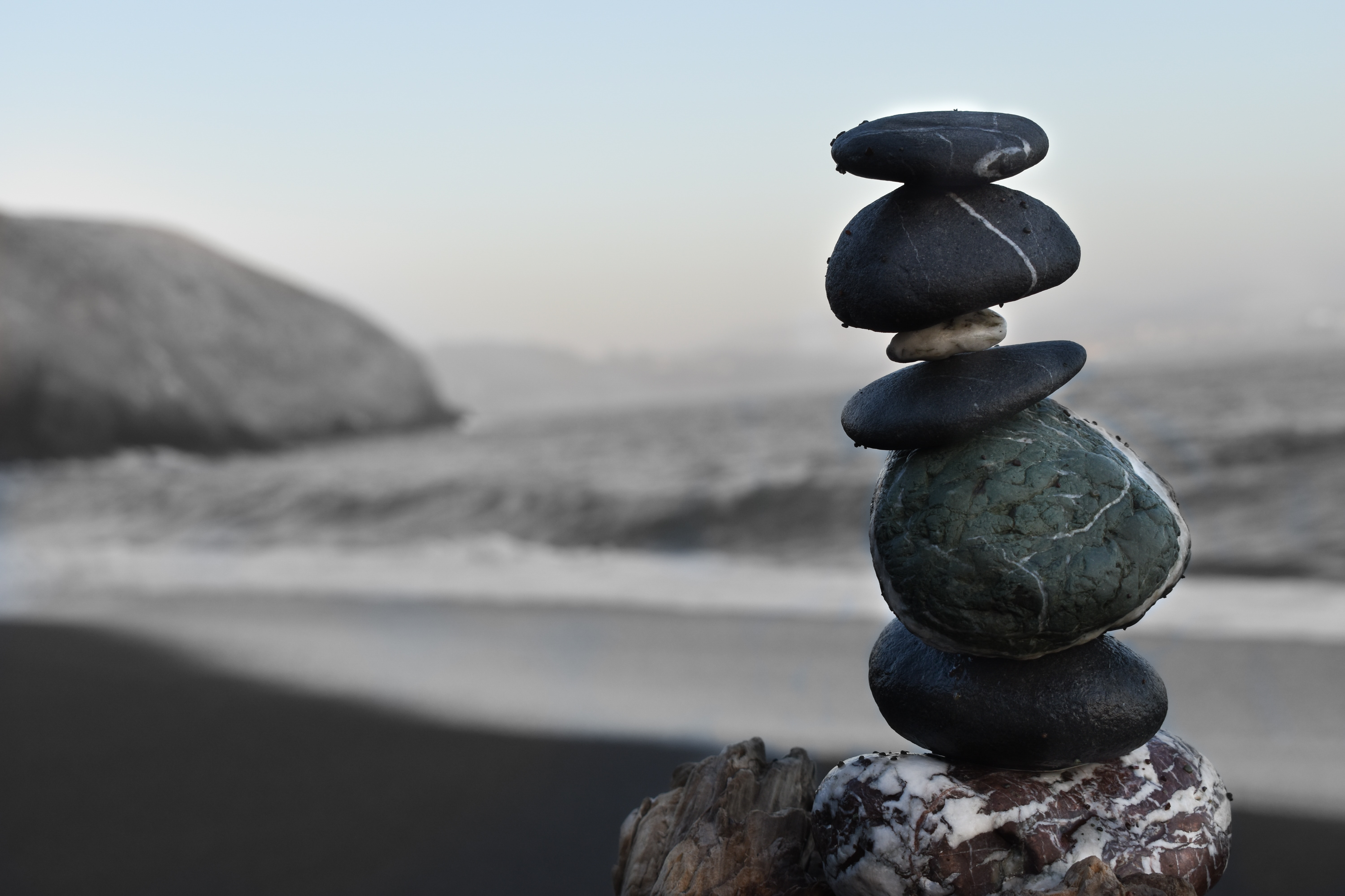 Rocks balanced on top of one another with the sea in the background. | Source: Unsplash