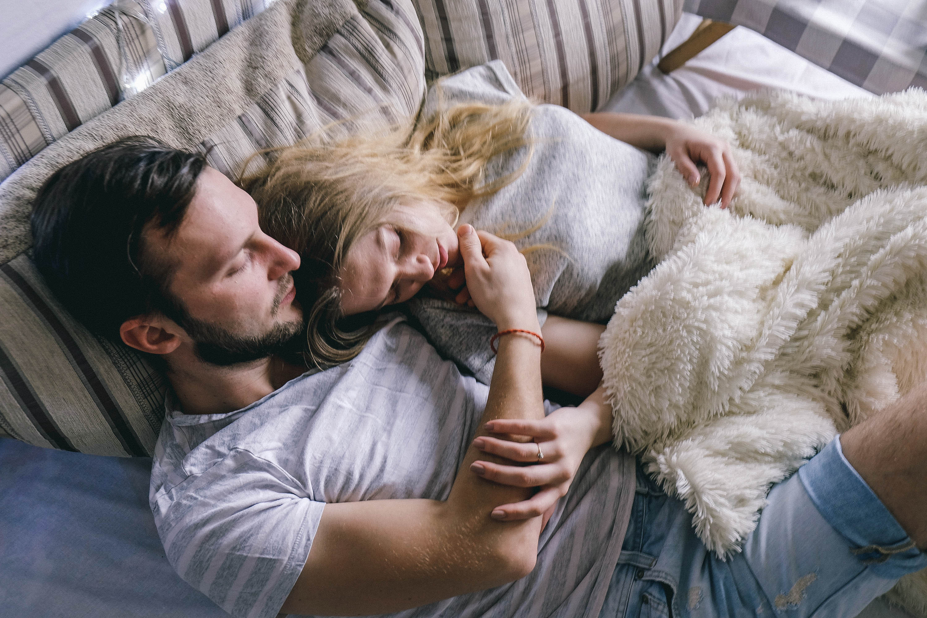 A young couple cuddling in bed | Source: Shutterstock