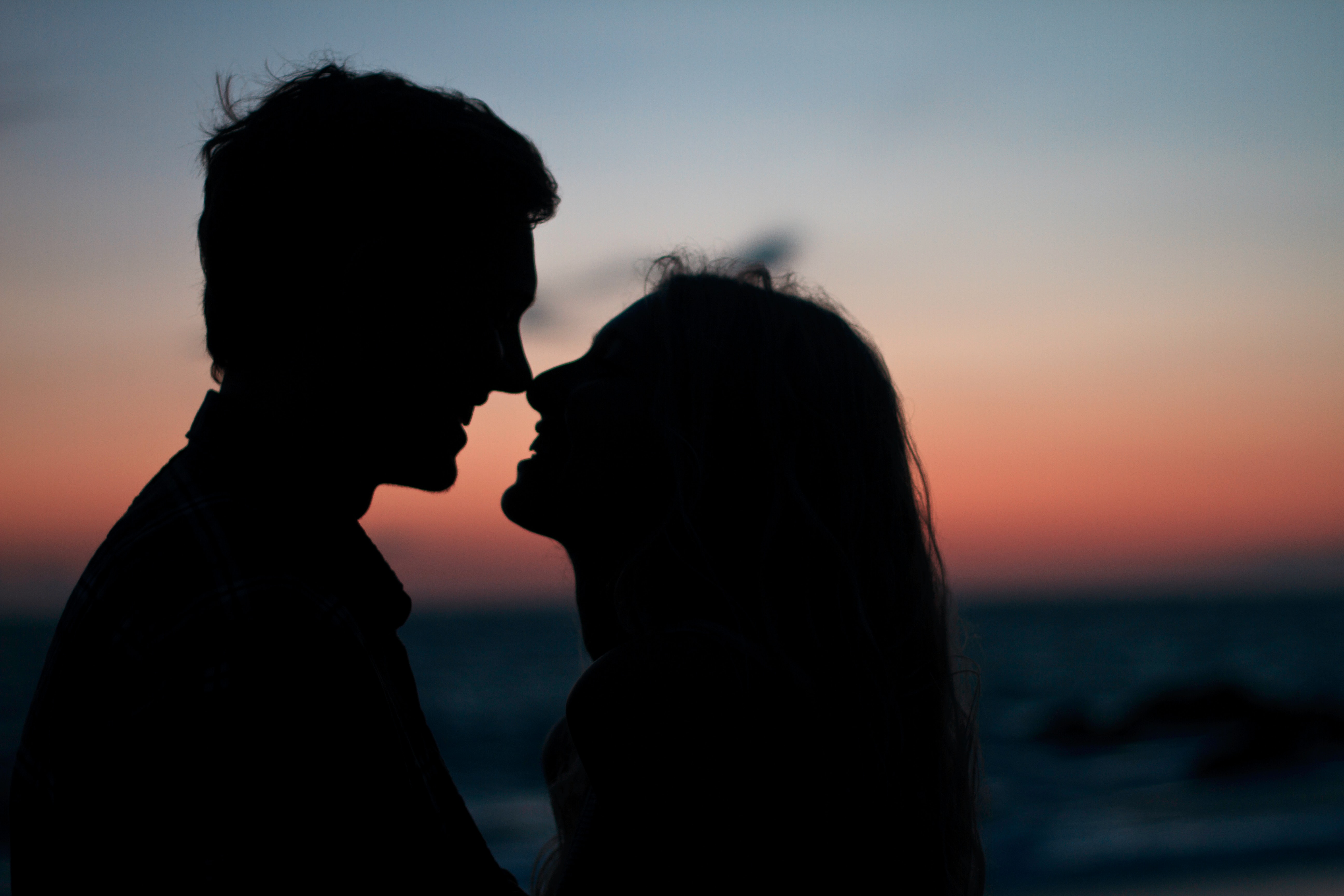 A couple laughing in front of the ocean. | Source: Unsplash