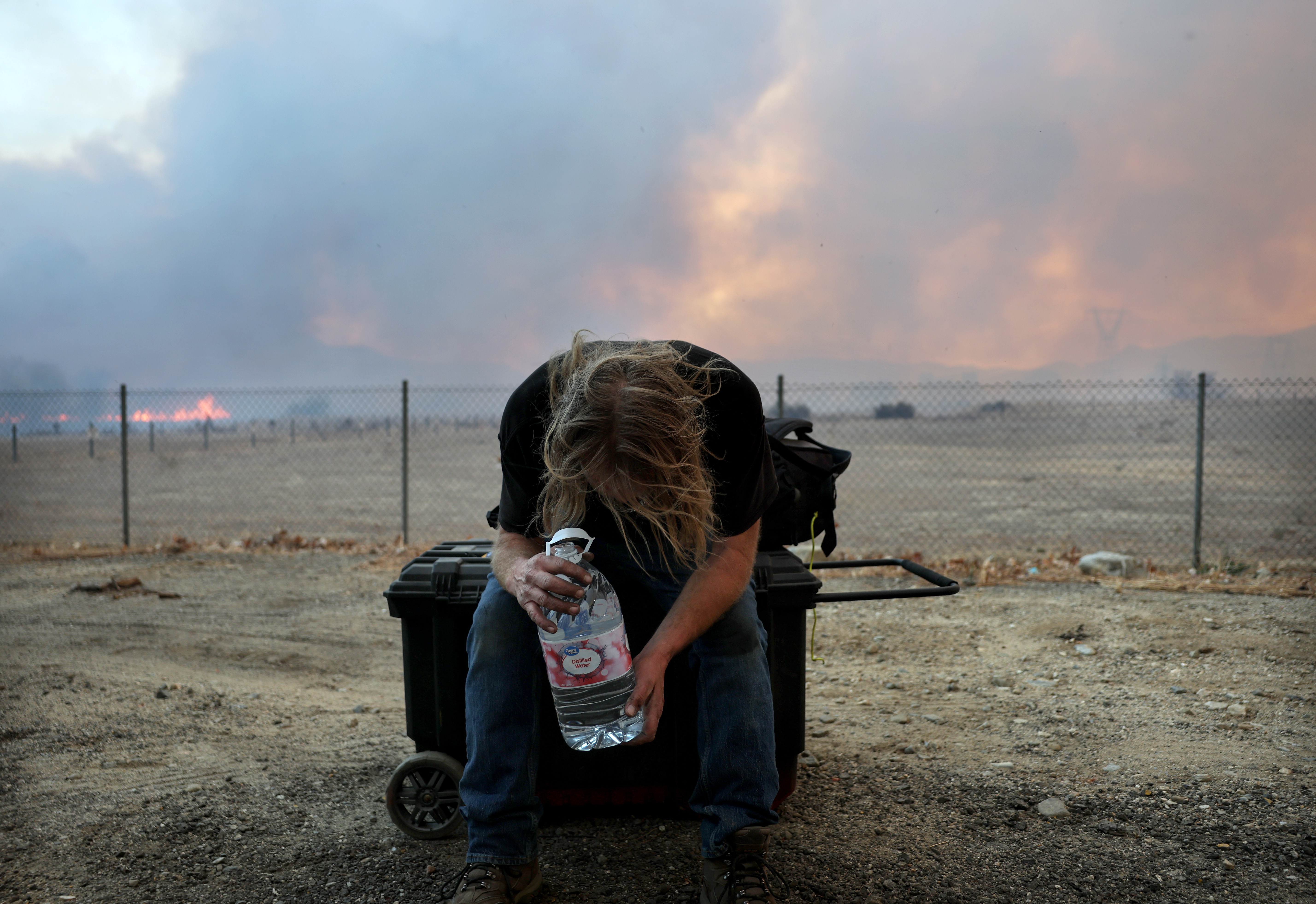 A man only identified as "Bruce" rests with a bottle of water after evacuating as the Hughes Fire burns north of Los Angeles on January 22, 2025, near Castaic, California | Source: Getty Images