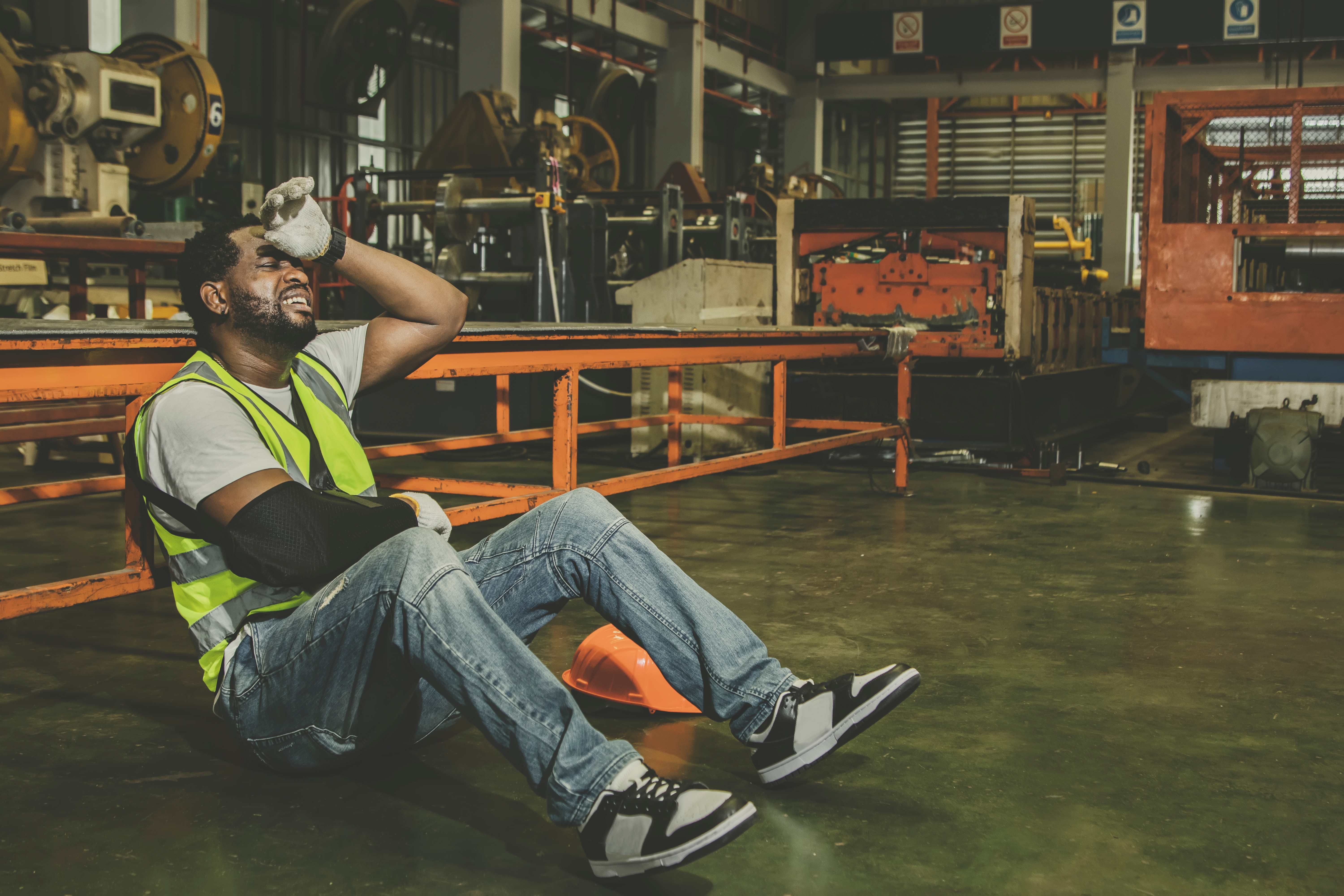 Un trabajador de una fábrica sentado en el suelo | Fuente: Shutterstock