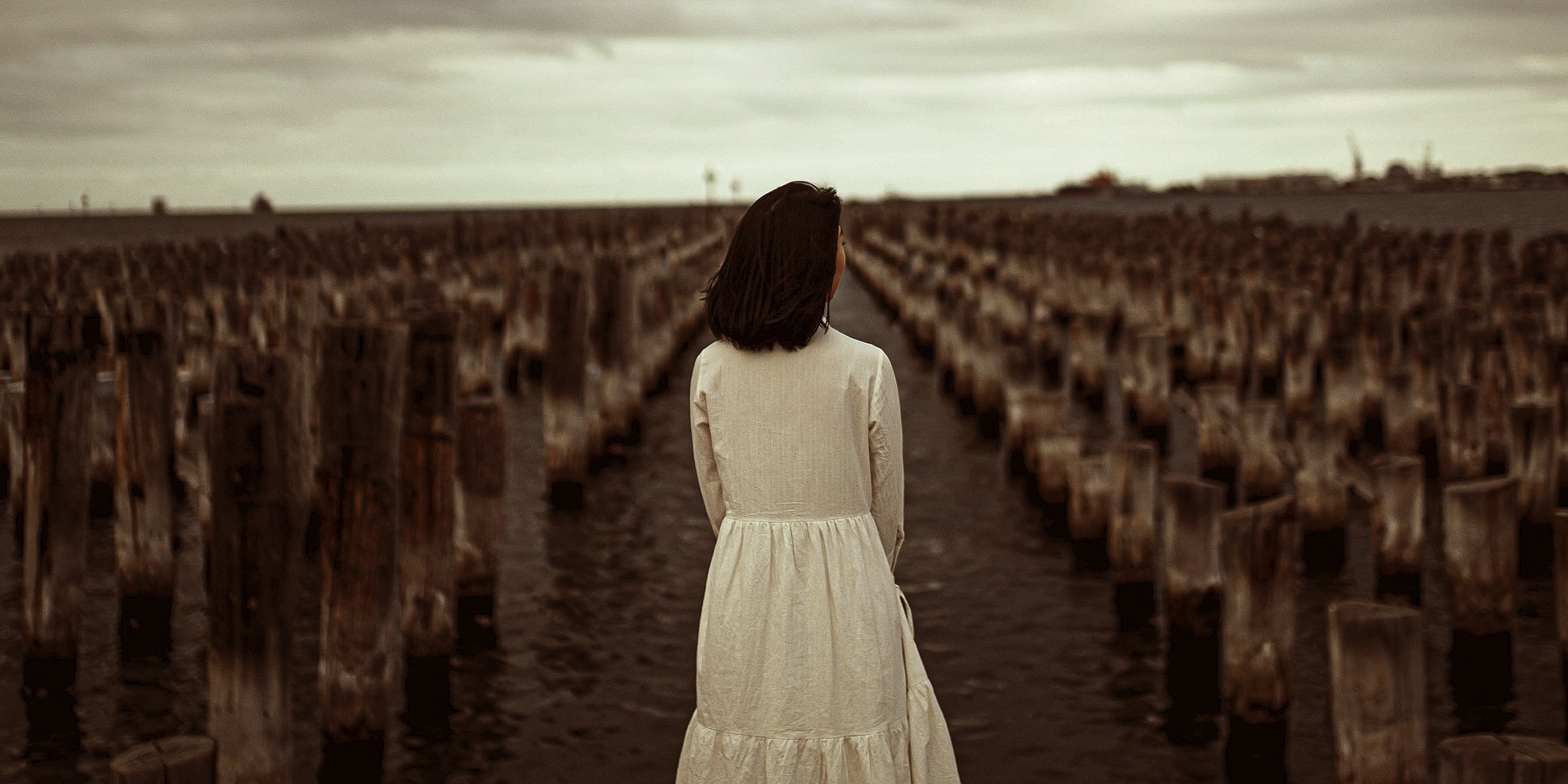 A woman looking in into the distance while standing in front of chopped down trees. | Source: Unsplash  