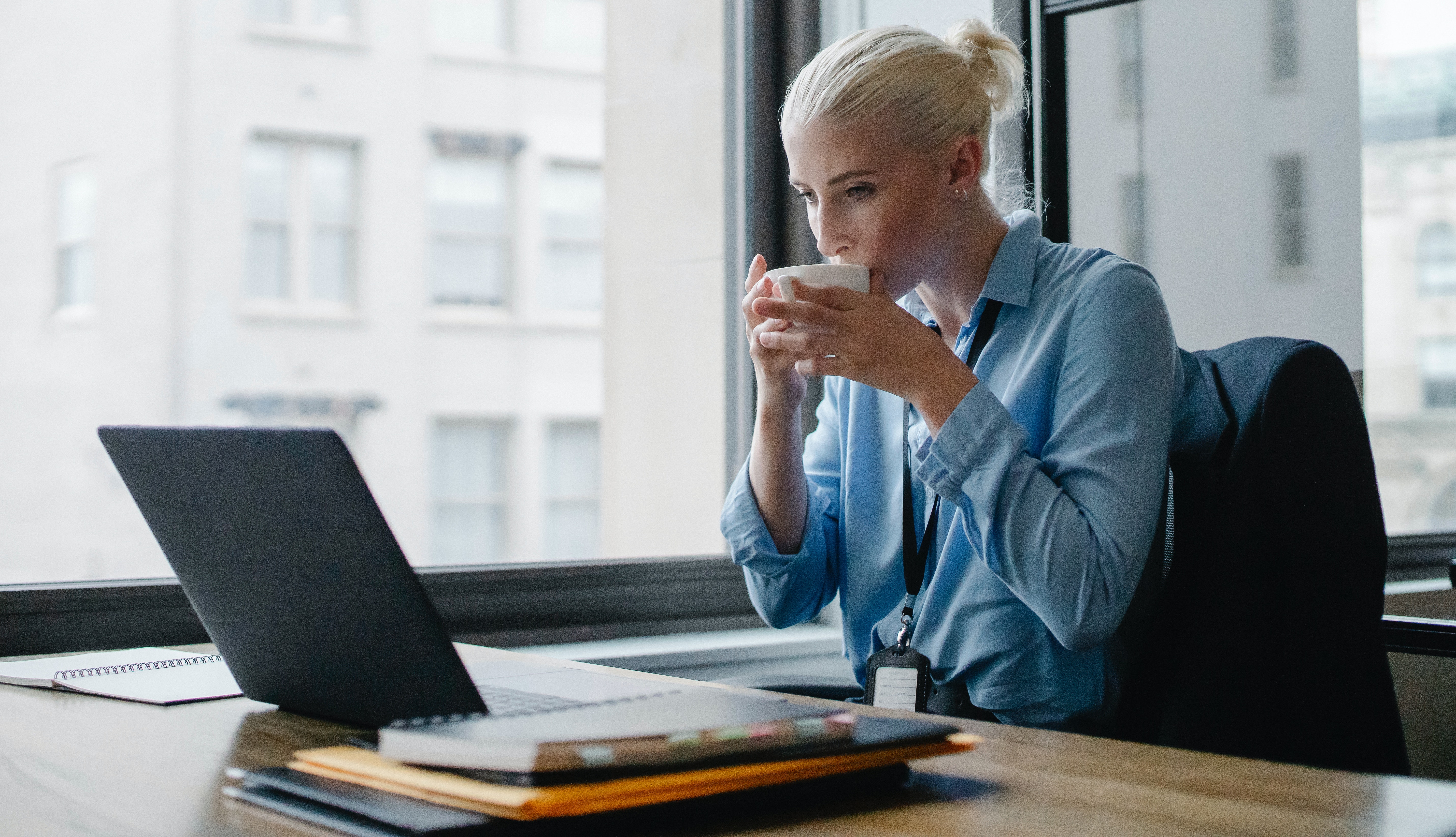 A woman working and sipping on coffee. | Source: Pexels