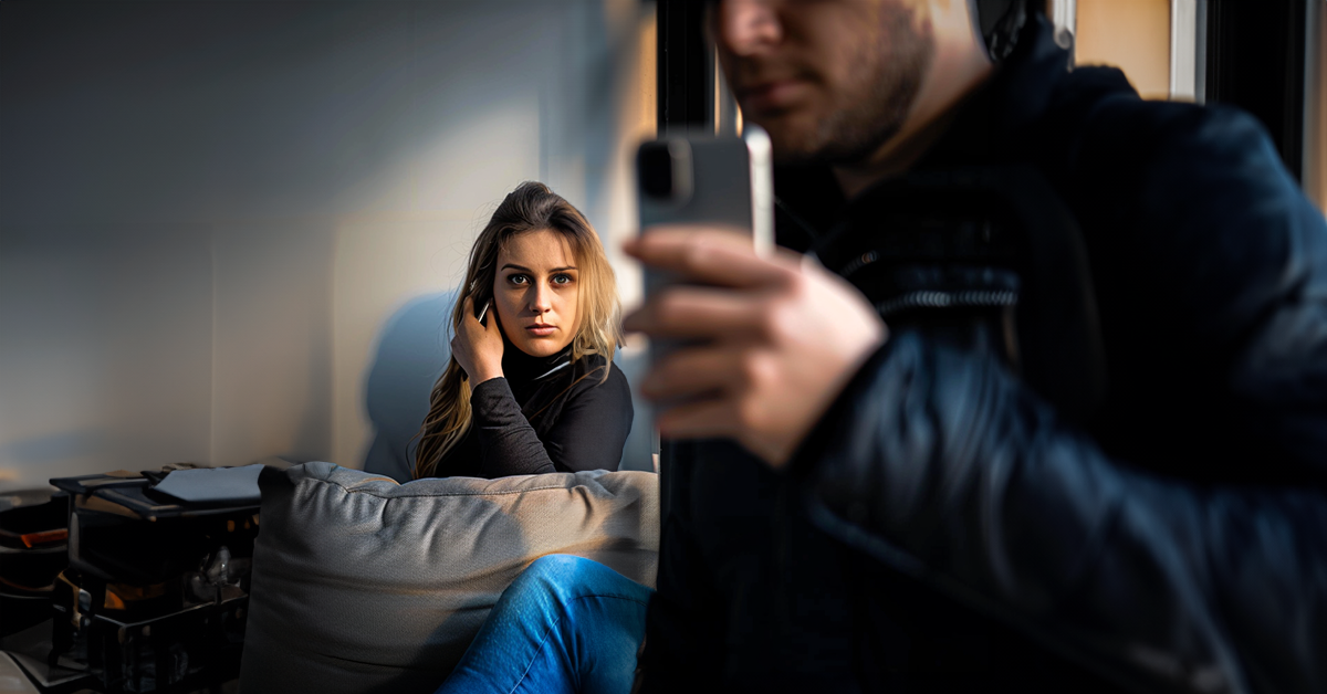 Mujer espiando detrás de un hombre con un teléfono | Fuente: Shutterstock