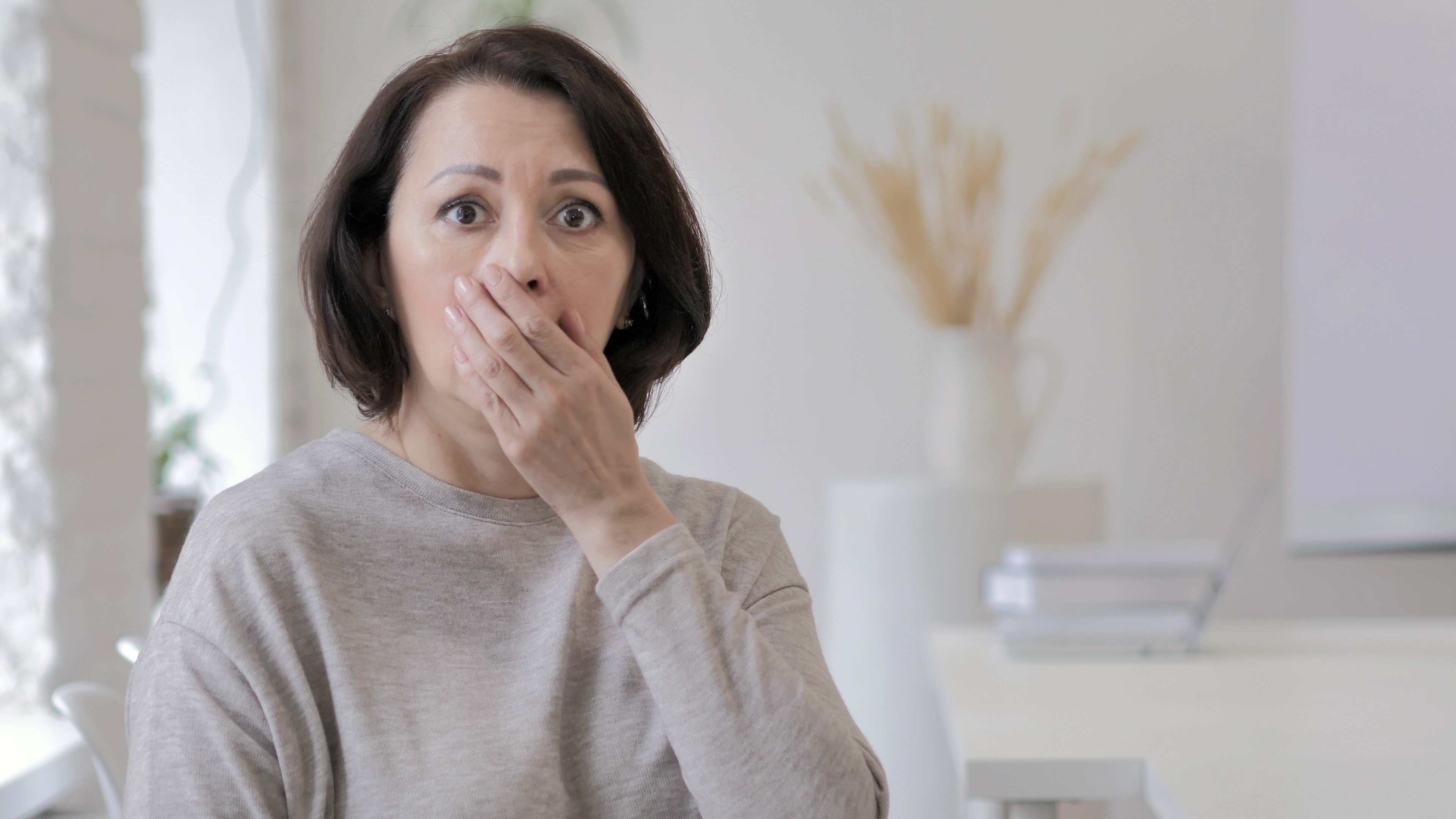 Una mujer conmocionada con la mano en la boca | Fuente: Shutterstock