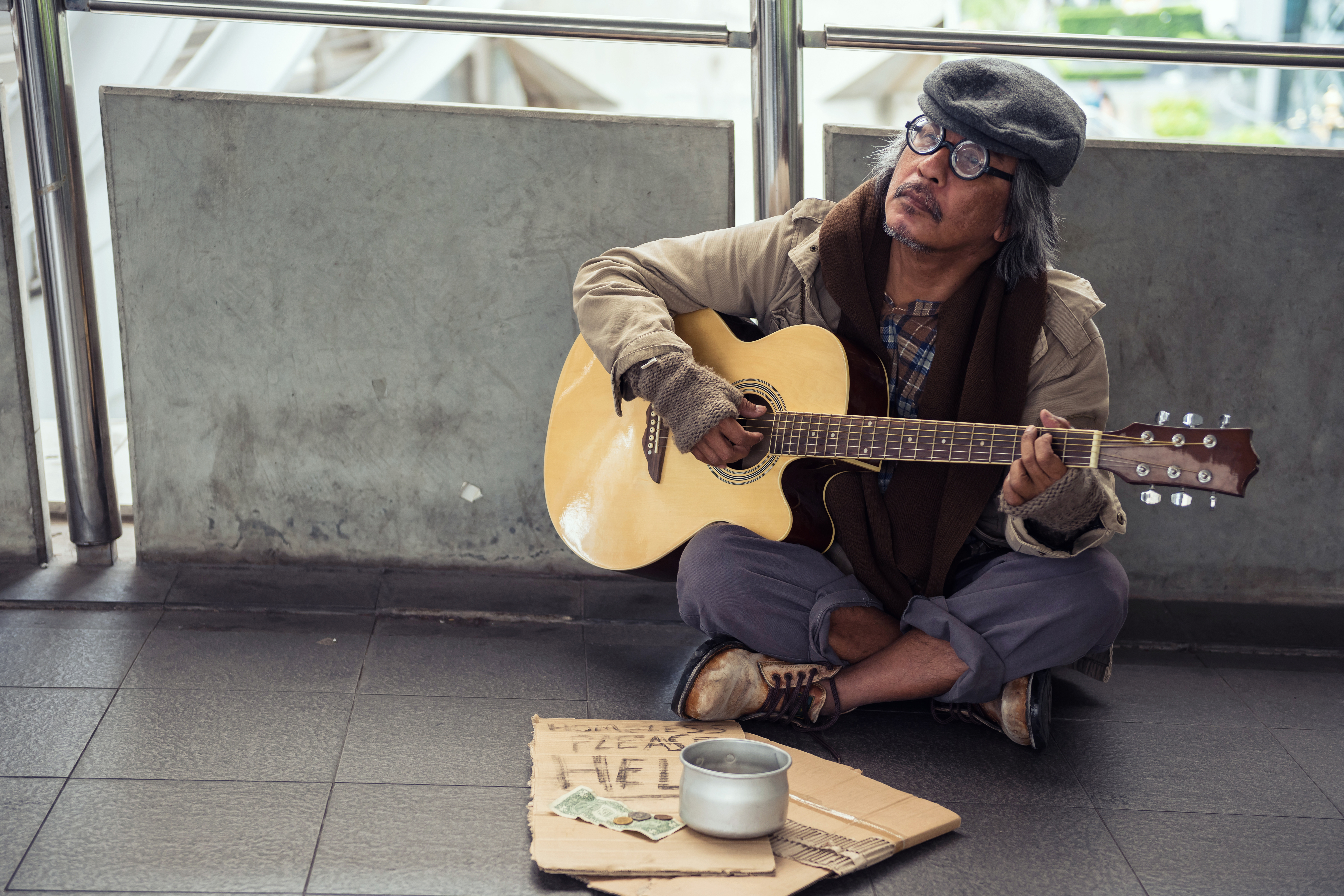 Viejo mendigo o anciano sin techo tocando la guitarra. | Fuente: Shutterstock