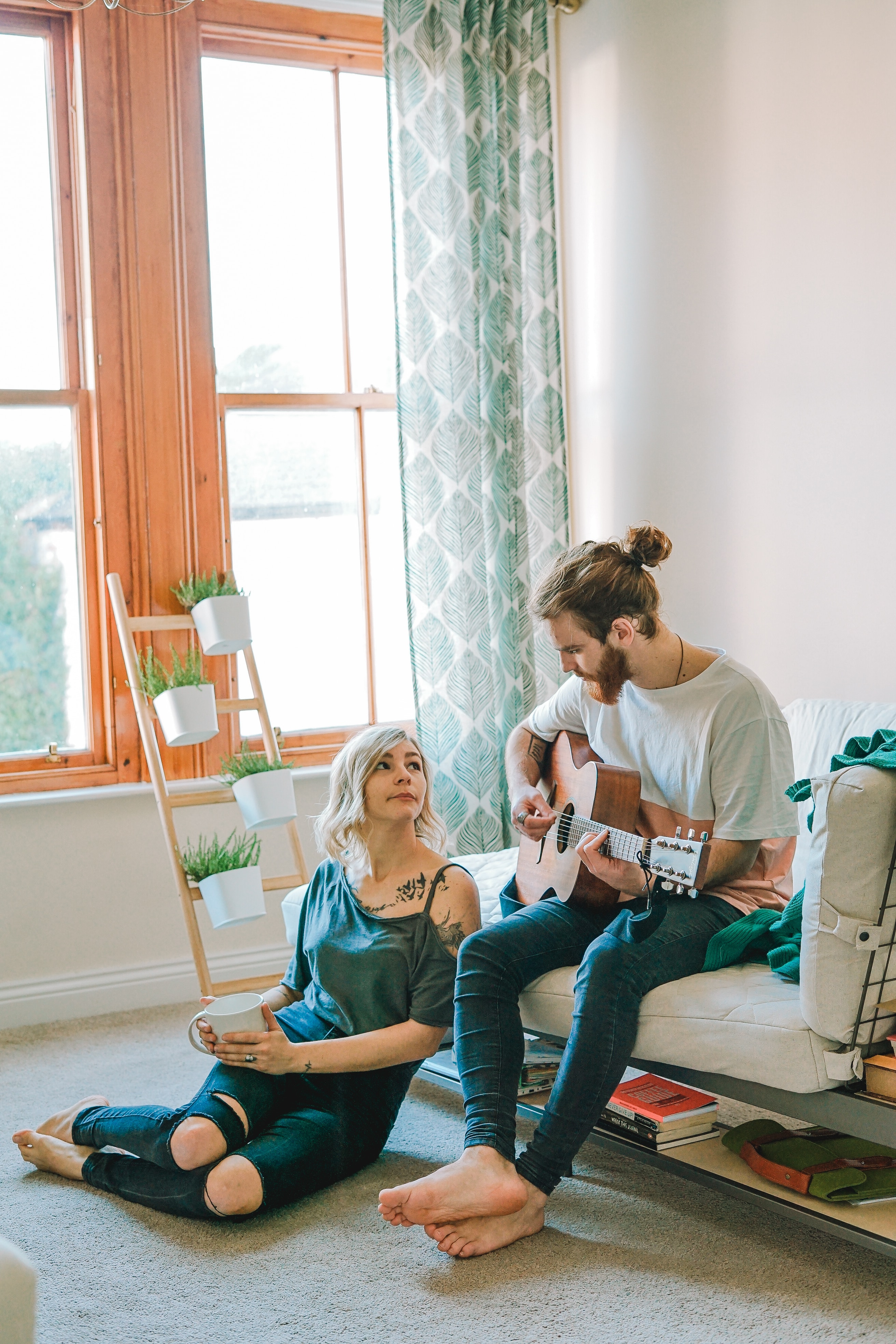 A couple sitting in a room with the man playing guitar. | Source: Unsplash