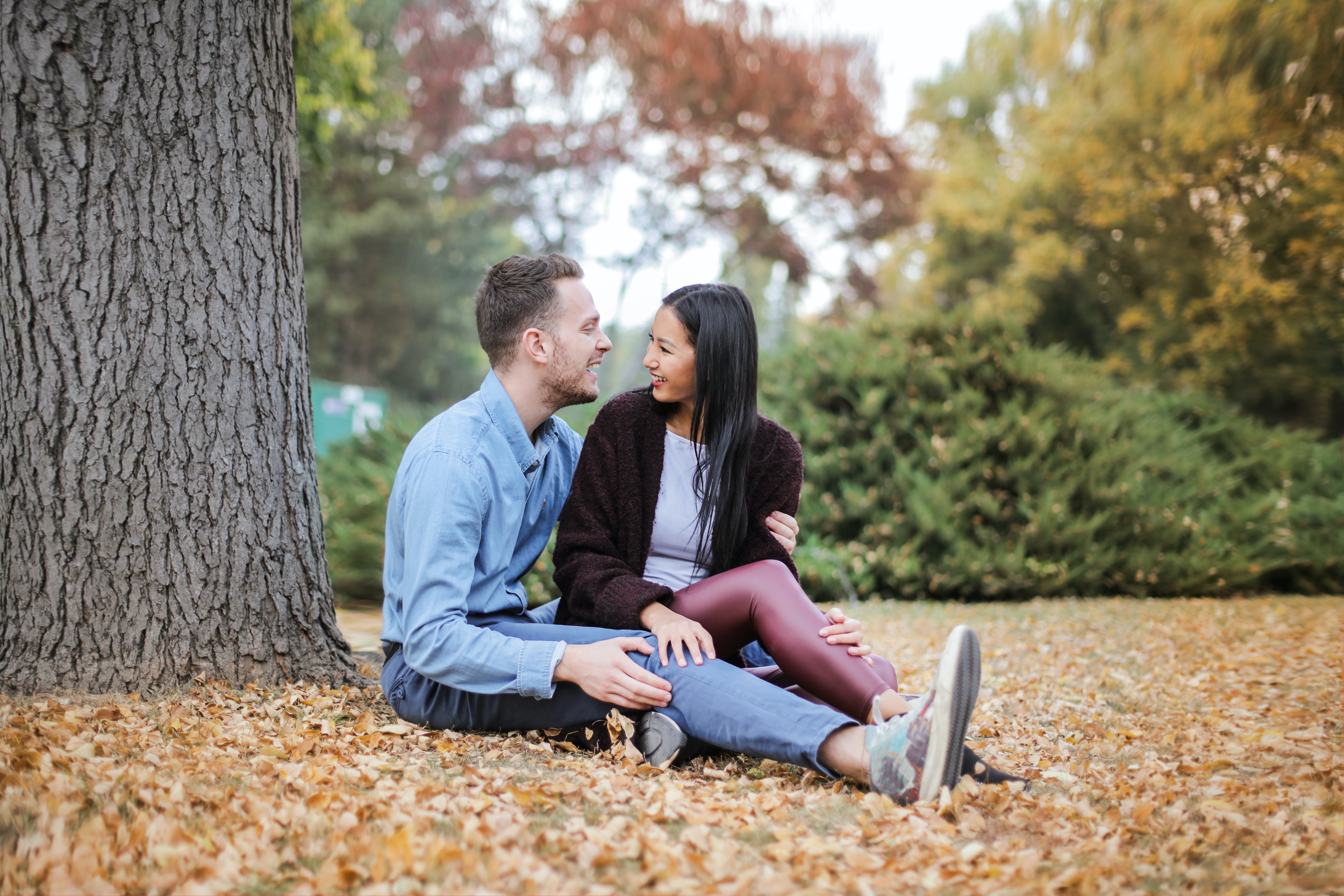 A couple smiling while sitting under a tree | Source: Pexels
