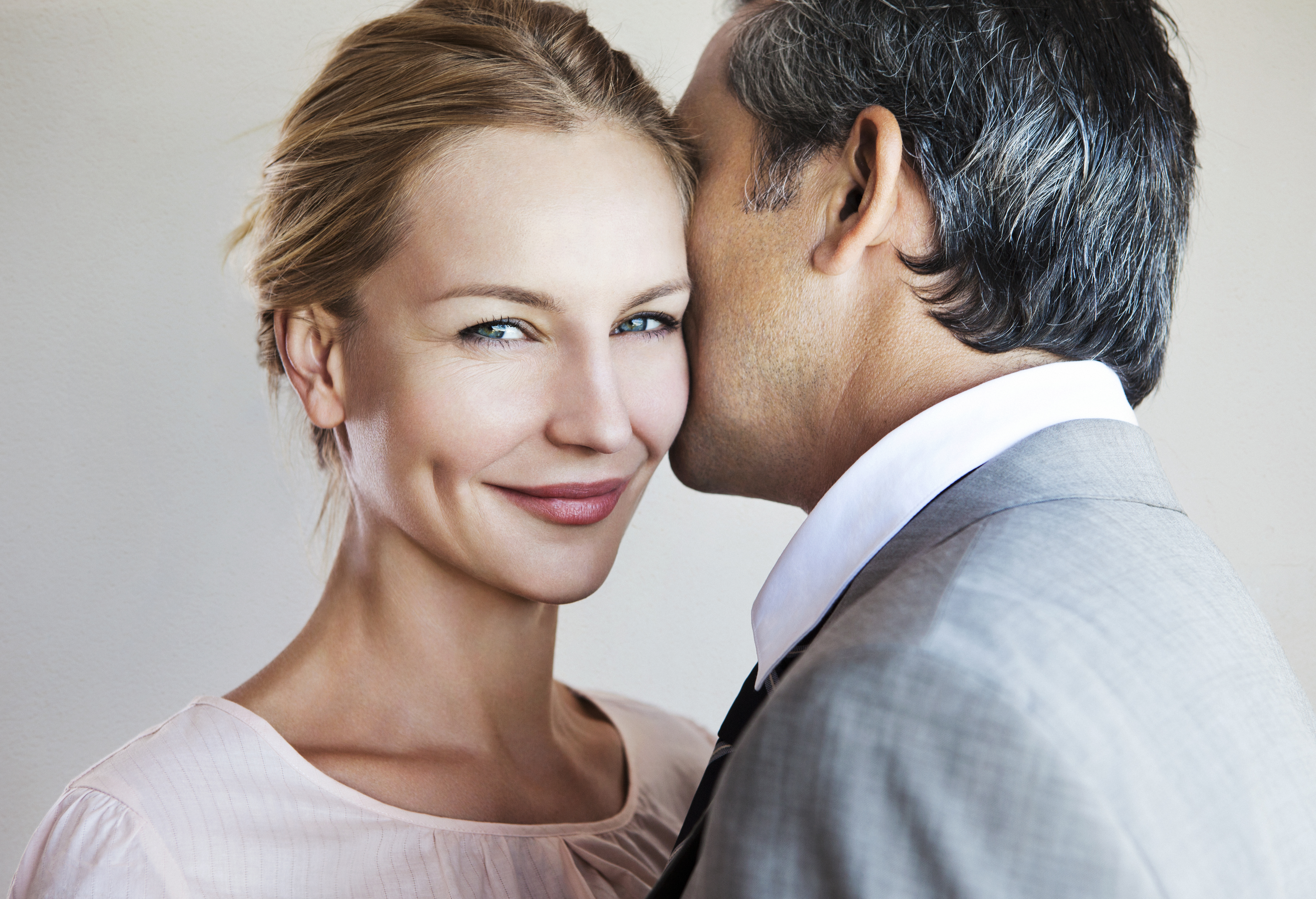A man whispering to a smiling woman. | Source: Getty Images