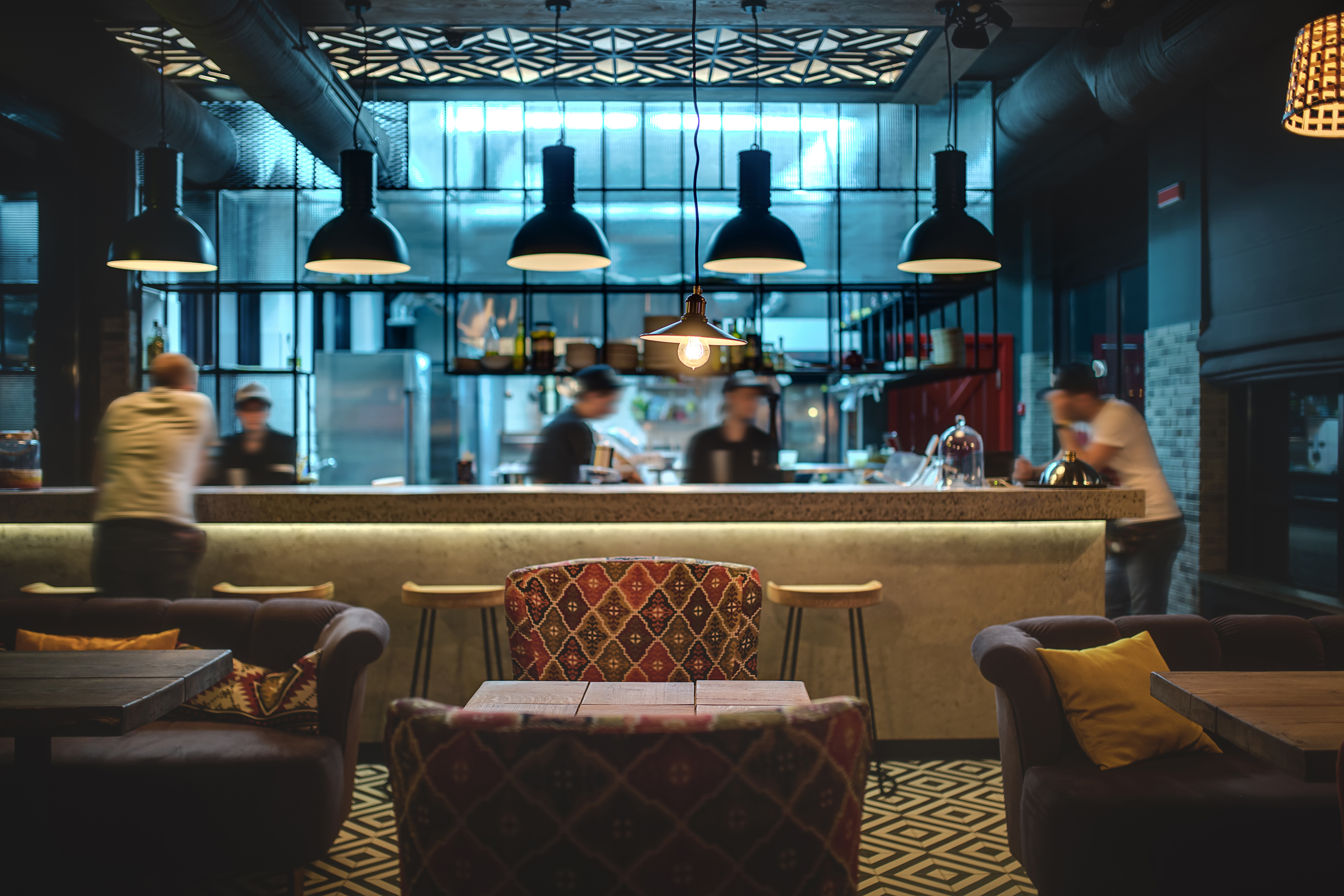 Salón a media luz estilo loft en un restaurante con cocina abierta al fondo. | Fuente: Shutterstock