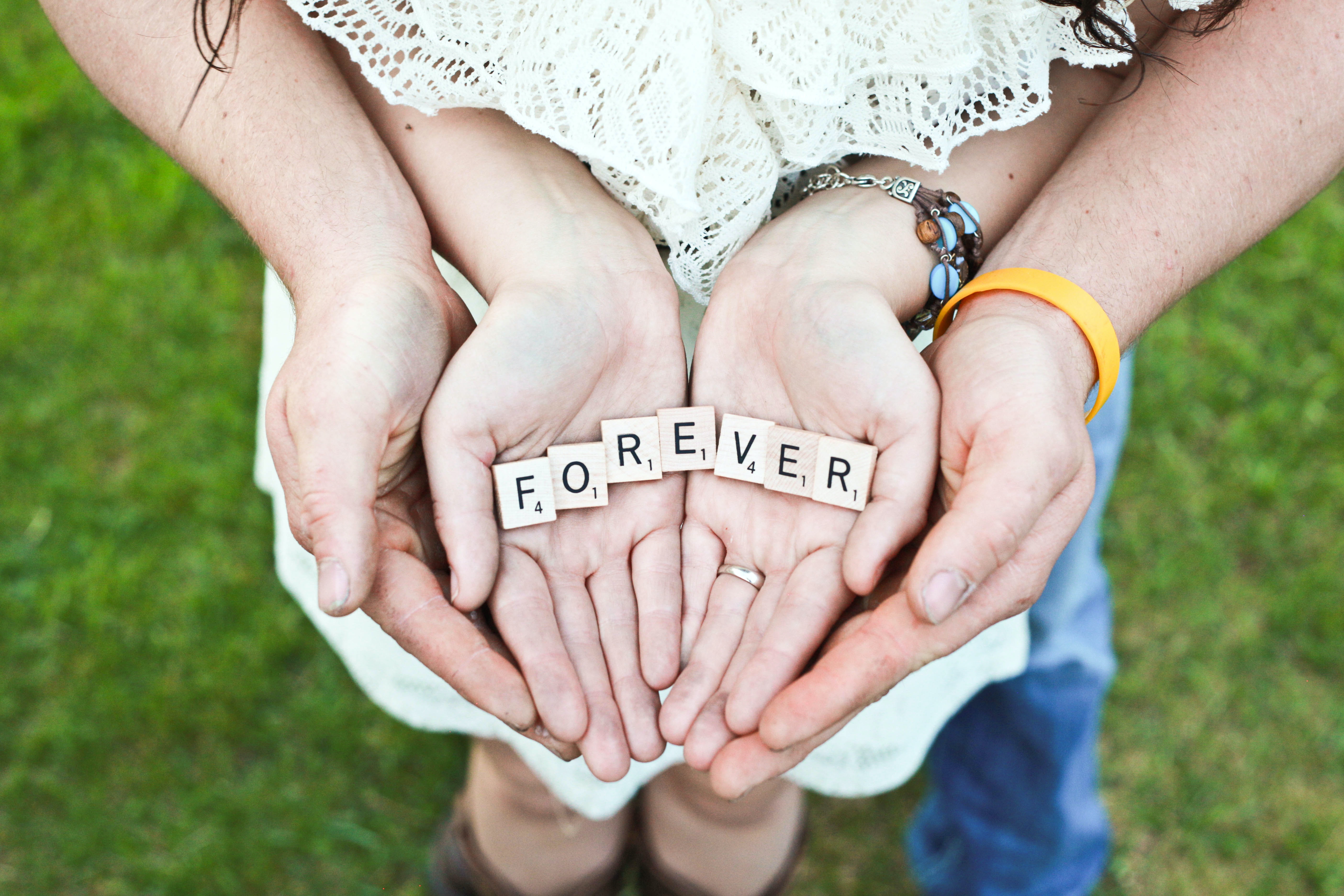 A photo of a woman holding scrabble letters with a man's hand underneath | Source: Unsplash