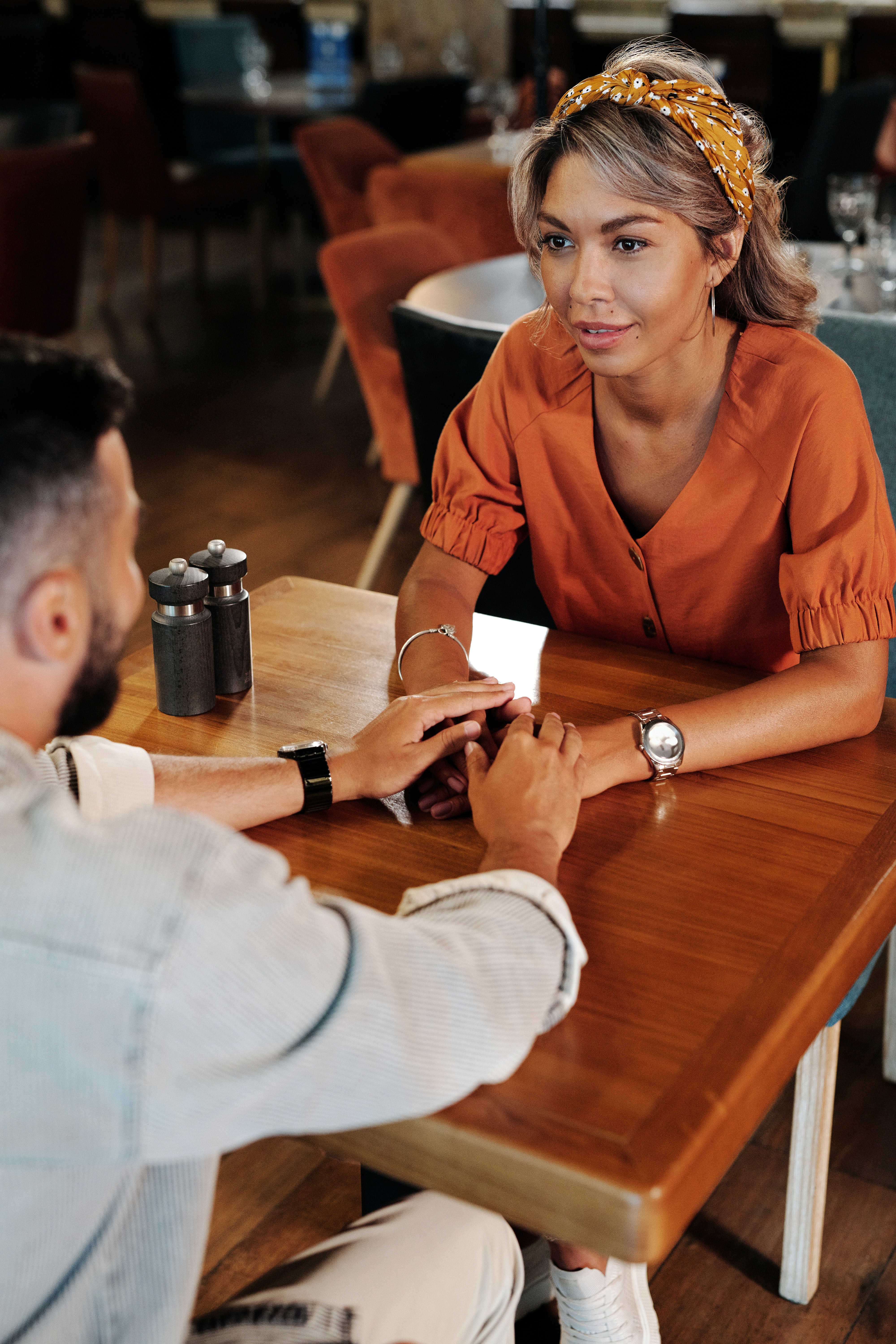 A couple holding hands on wooden table. | Source: Pexels