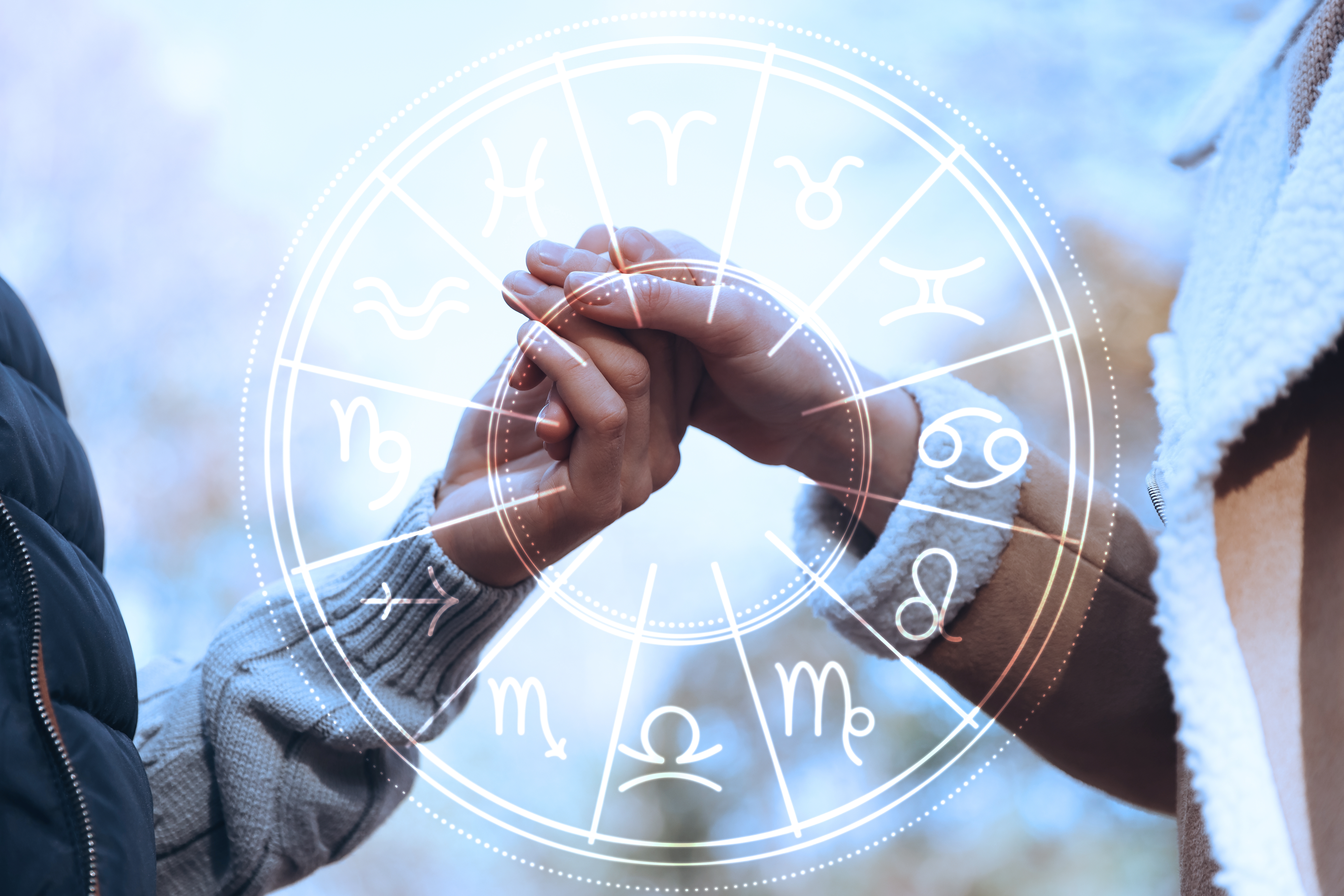 Horoscope compatibility: A loving couple holding hands outdoors and zodiac wheel. | Source: Shutterstock