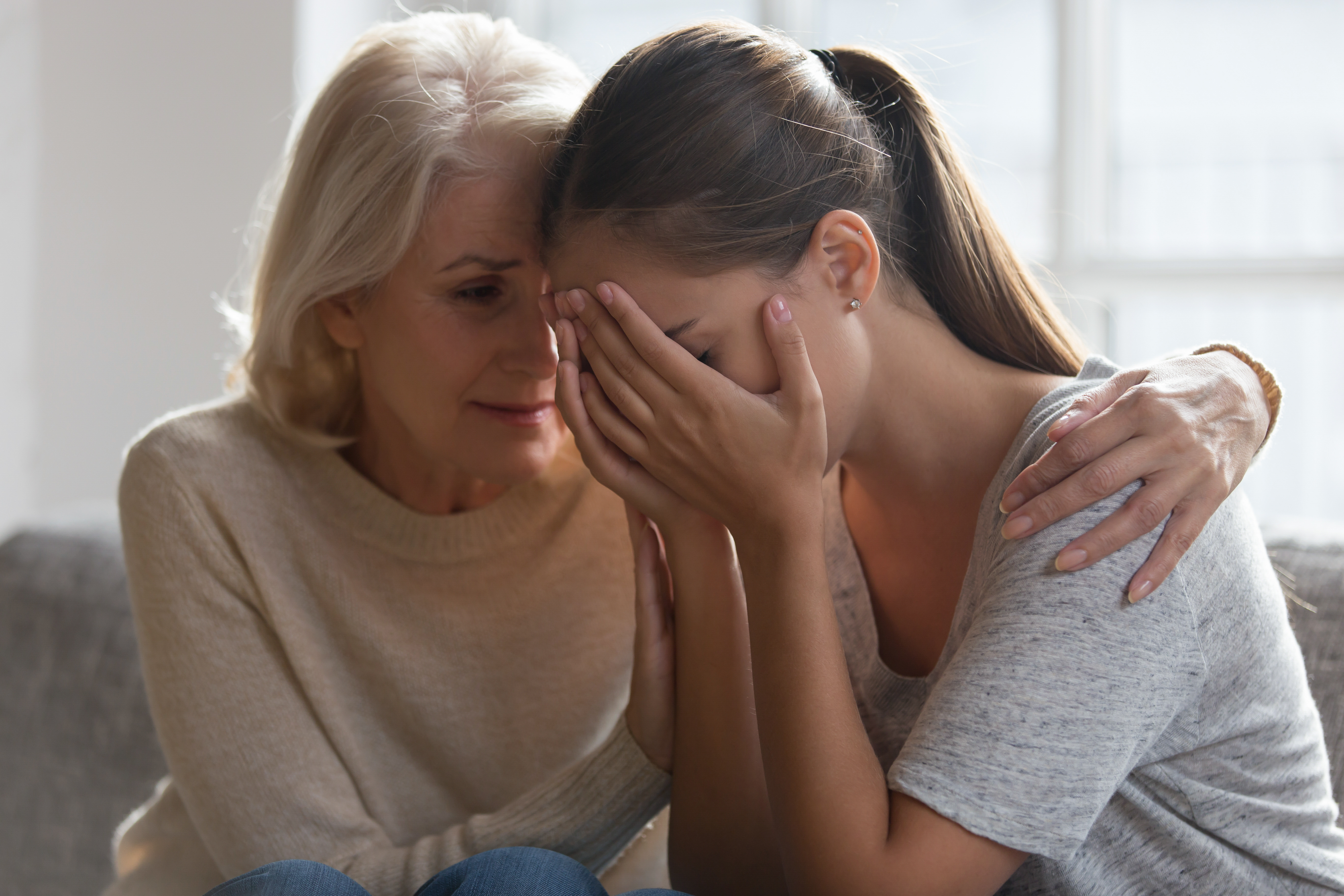 Worried aged mother embracing comforting grown up daughter with broken heart. | Source: Shutterstock