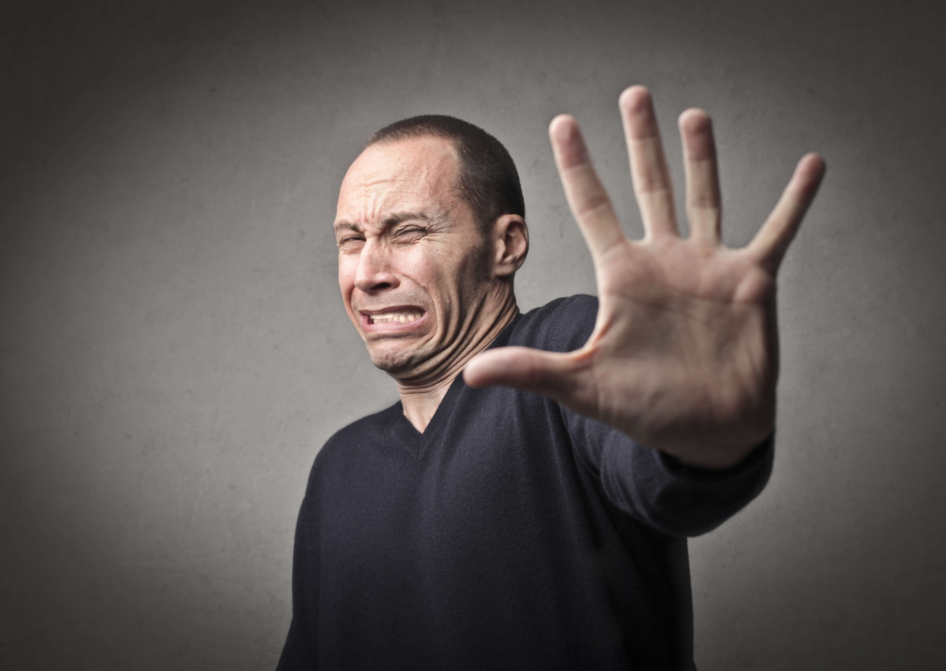 Hombre asustado indicando que se detenga con la mano | Fuente: Shutterstock.com