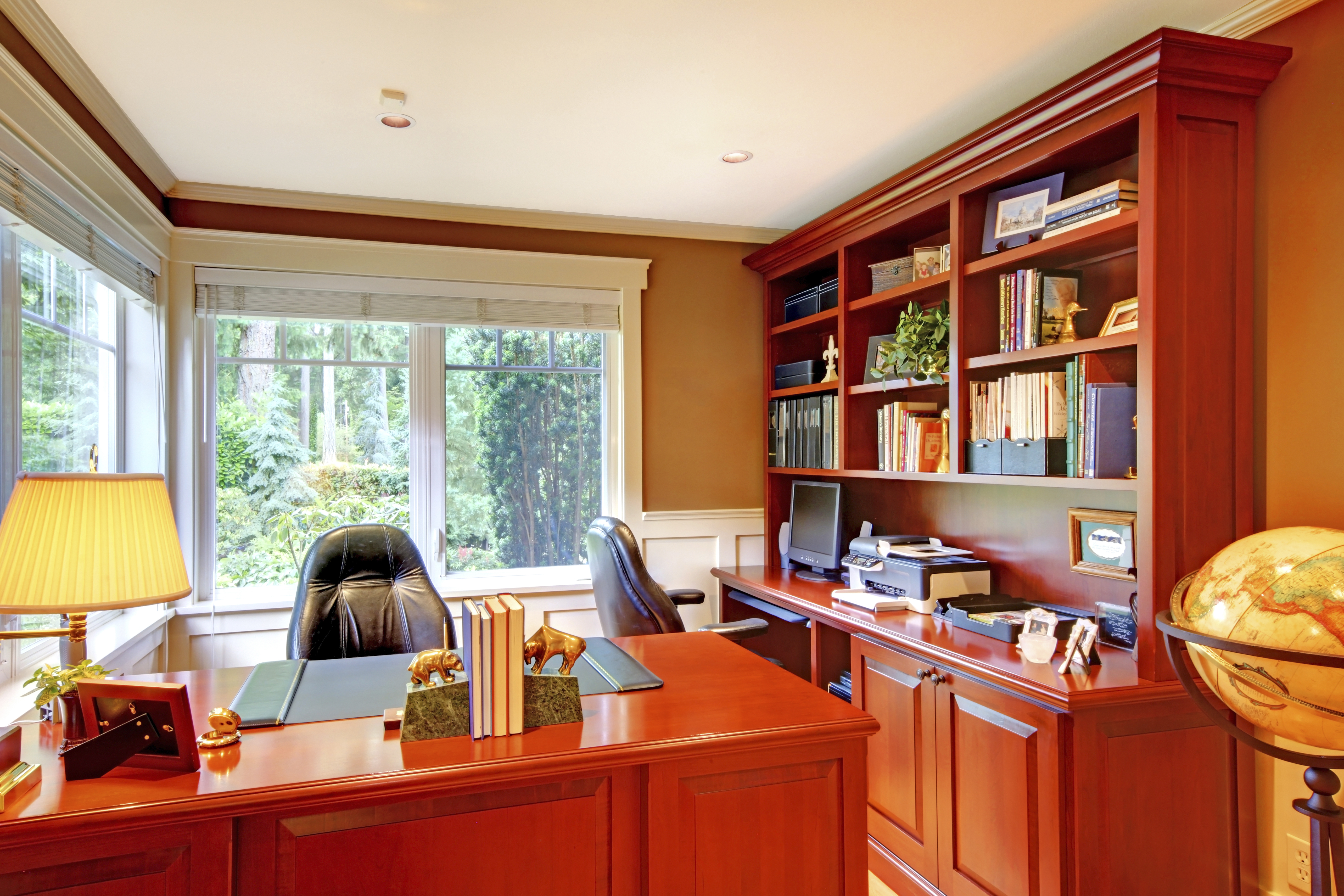 Interior de oficina de lujo con paredes grises y madera. Amueblado con escritorio de madera y sillas de cuero. | Fuente: Shutterstock