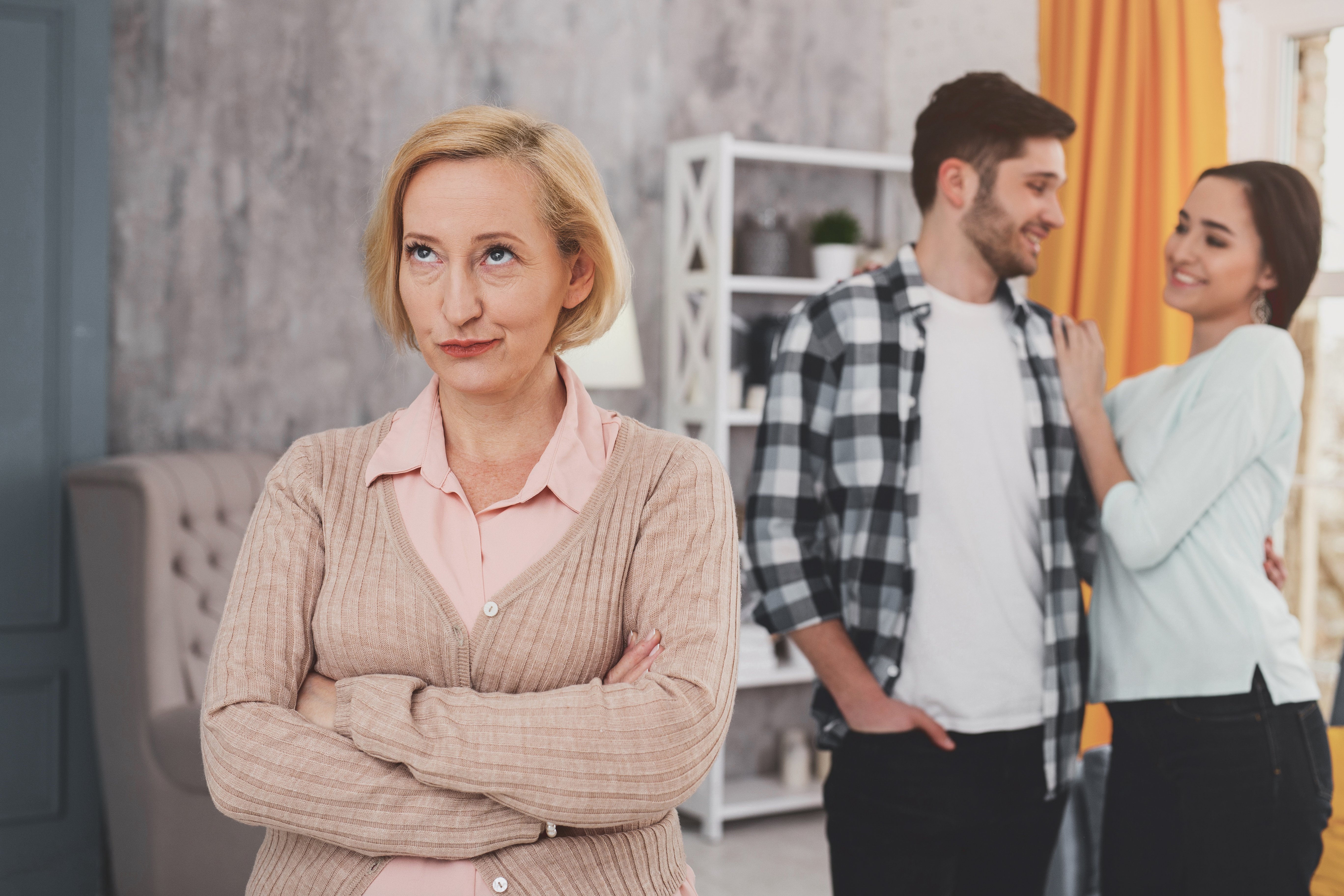 Una pareja feliz detrás de una mujer mayor disgustada | Fuente: Shutterstock