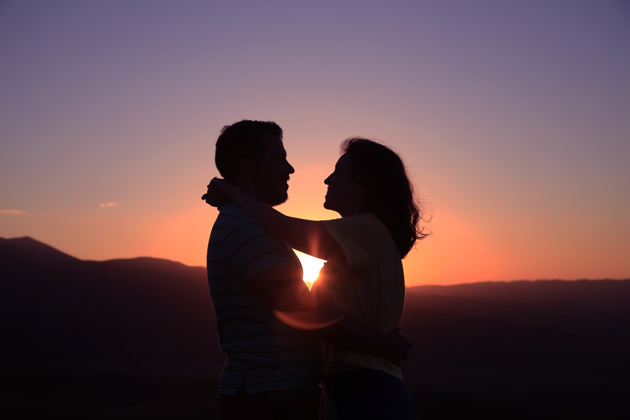 Couple embracing in frontof the sunset. | Source: Unsplash