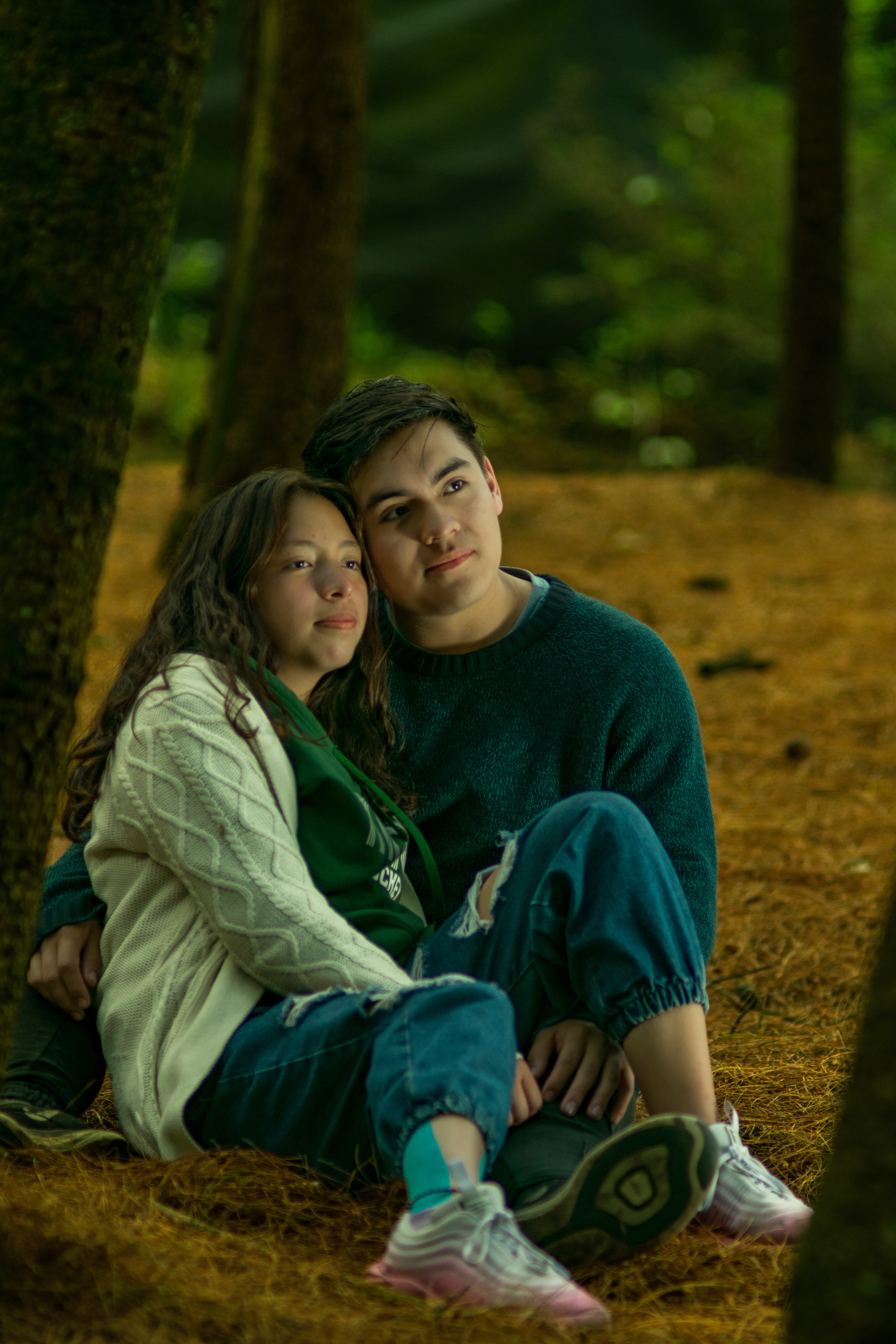 Embracing Young Couple Sitting on the Ground in the Forest. | Source: Pexels