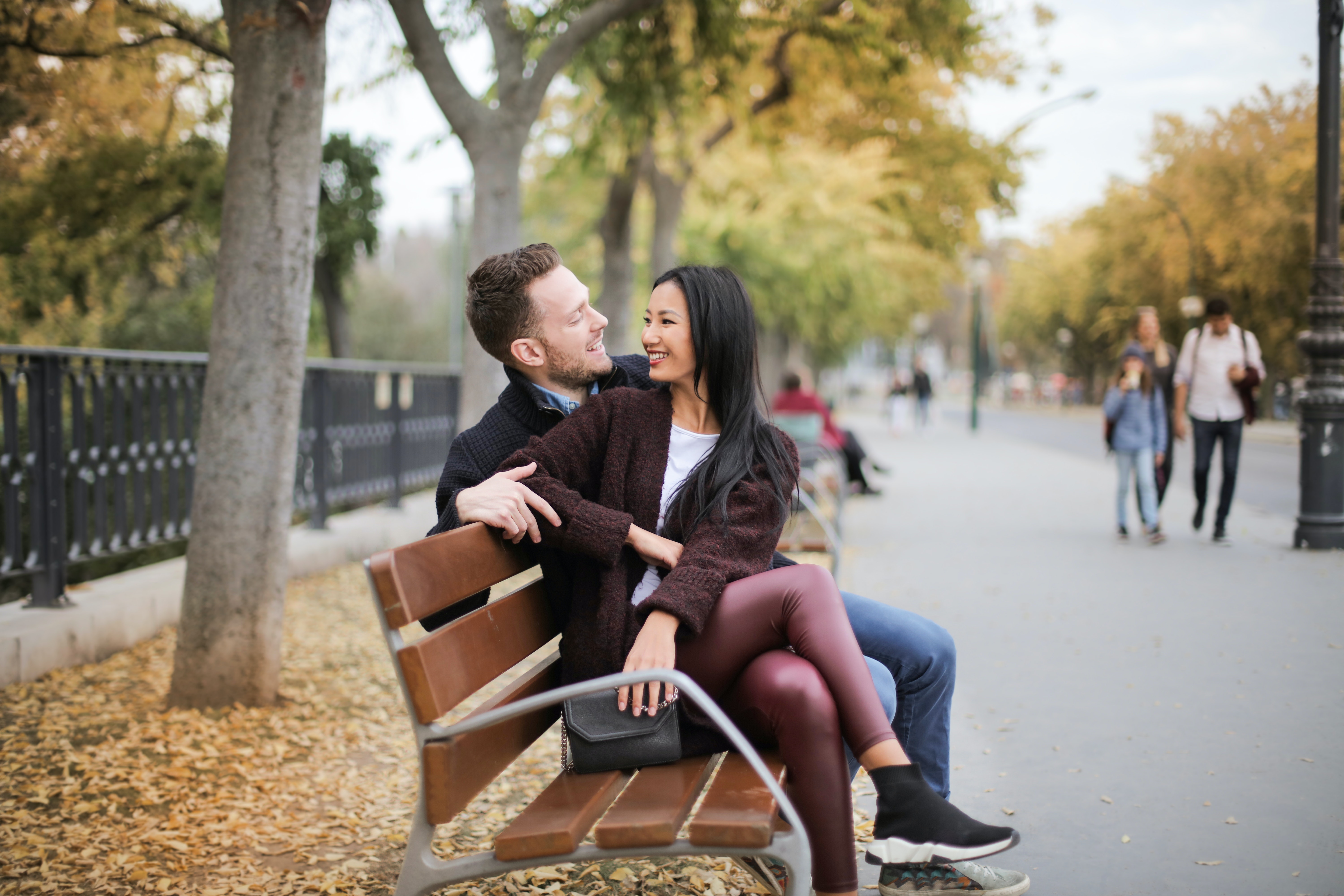 Couple sitting on wooden bench. | Source: Pexels